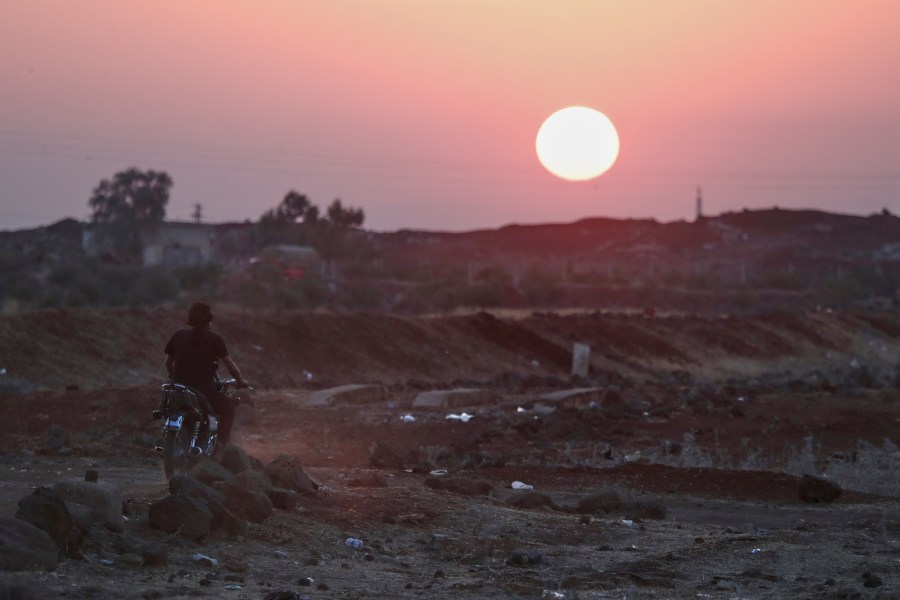 A Bedouin fighter rides a motorcycle as the sun sets over the village of Busra al-Harir, southern Syria, Tuesday, July 22, 2025. (AP Photo/Omar Sanadiki)