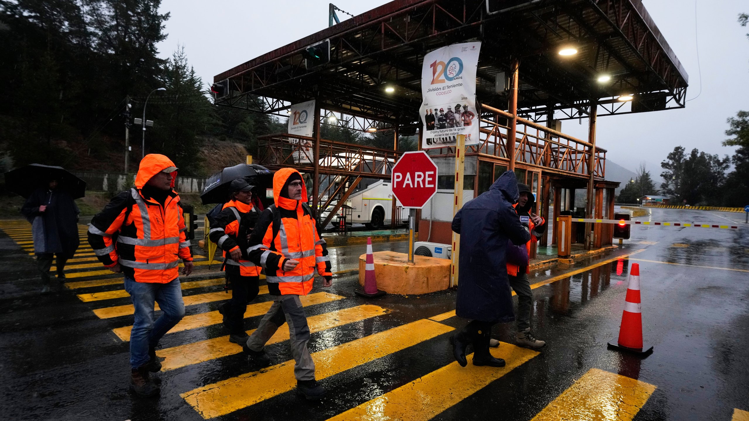 Workers walk at the entrance of El Teniente copper mine, operated by Codelco in Chile, where a collapse killed one worker and trapped five others underground, leading to a suspension of operations in Rancagua Chile, Friday, Aug. 1, 2025. (AP Photo/Esteban Felix)