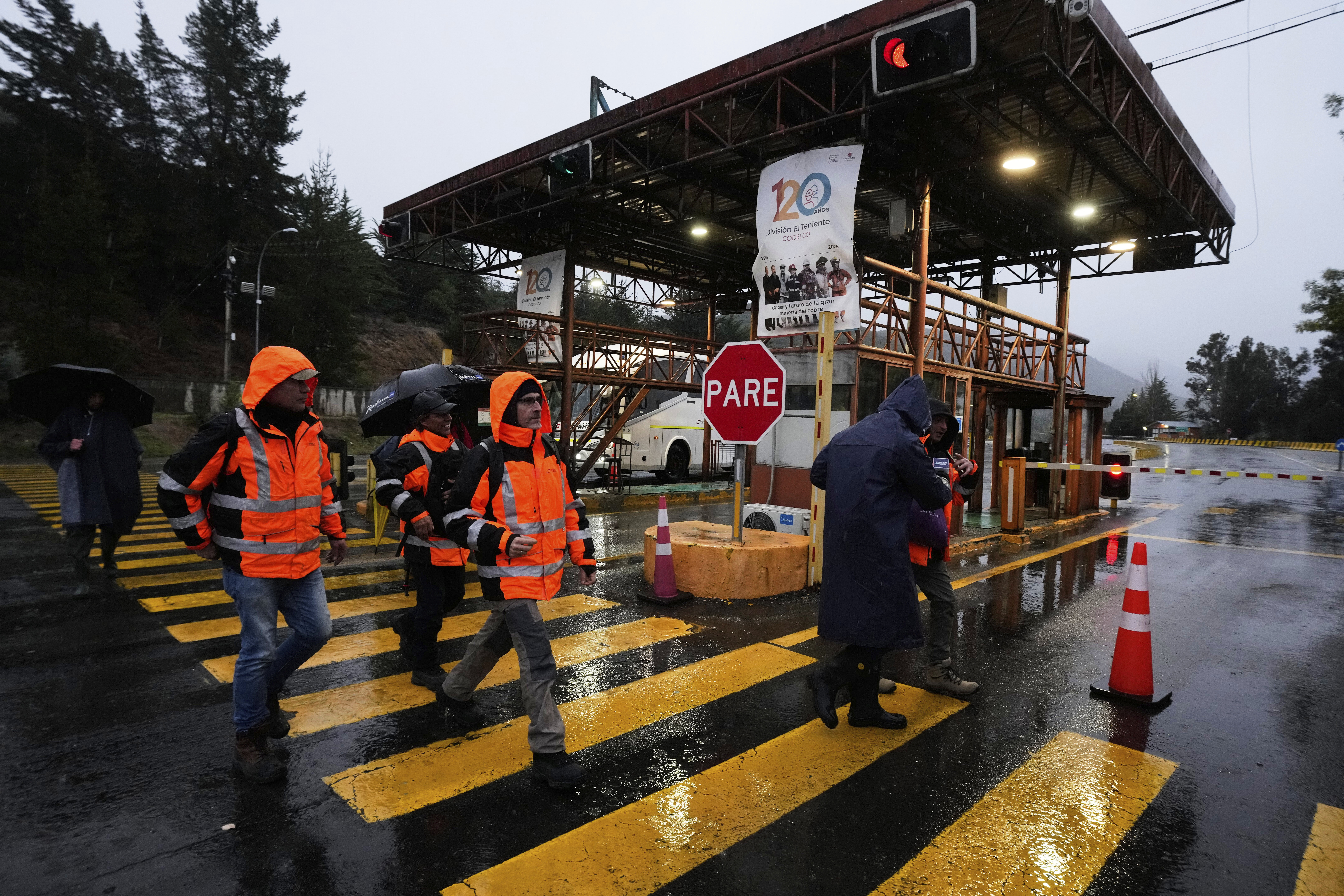 Workers walk at the entrance of El Teniente copper mine, operated by Codelco in Chile, where a collapse killed one worker and trapped five others underground, leading to a suspension of operations in Rancagua Chile, Friday, Aug. 1, 2025. (AP Photo/Esteban Felix)