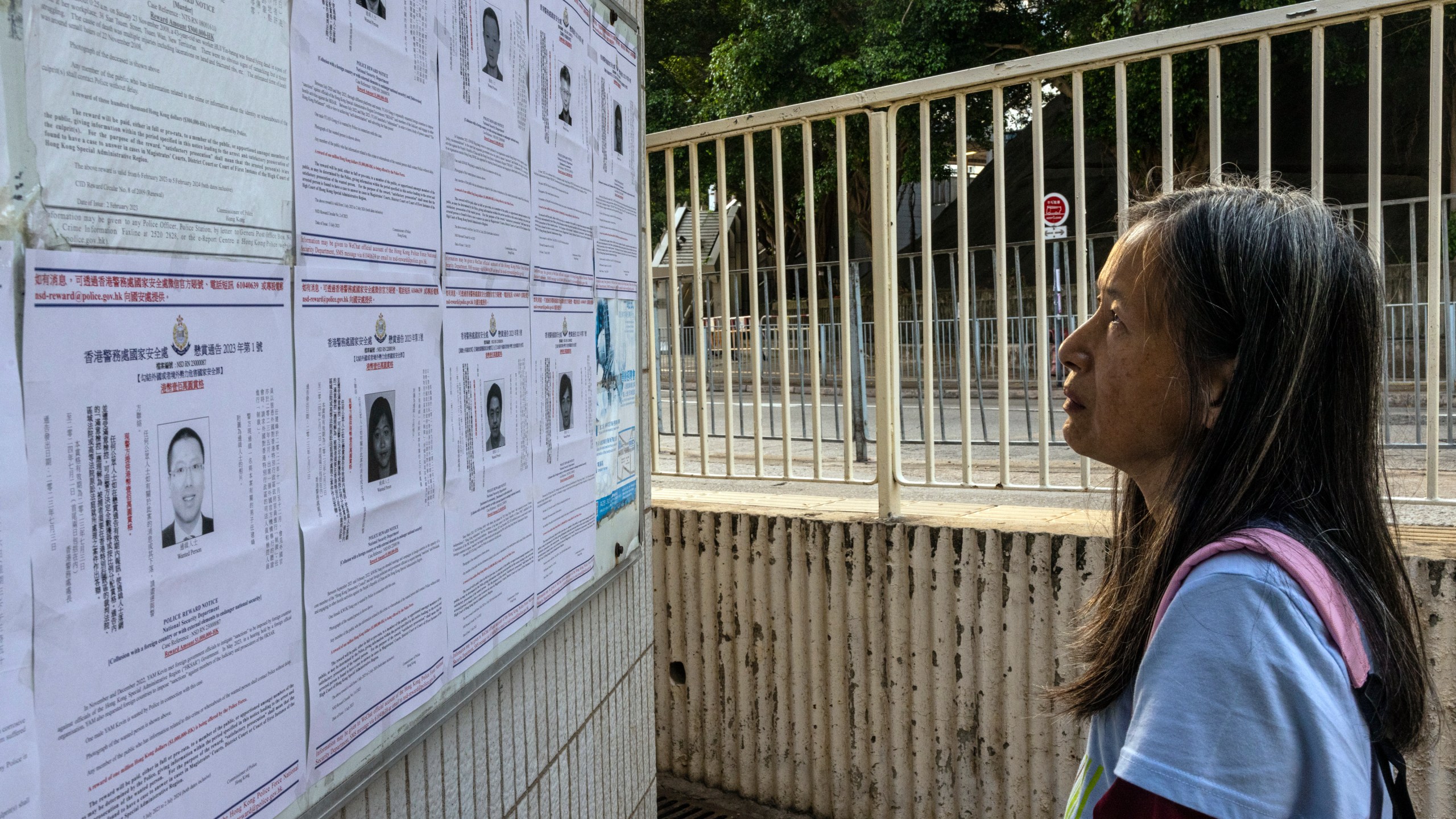 FILE - A pedestrian looks at the police reward notices for the arrest warrants issued for eight pro-democracy activists living in the United States, Britain, Canada and Australia for alleged national security offenses in Hong Kong, Friday, July 14, 2023. (AP Photo/Louise Delmotte, File)