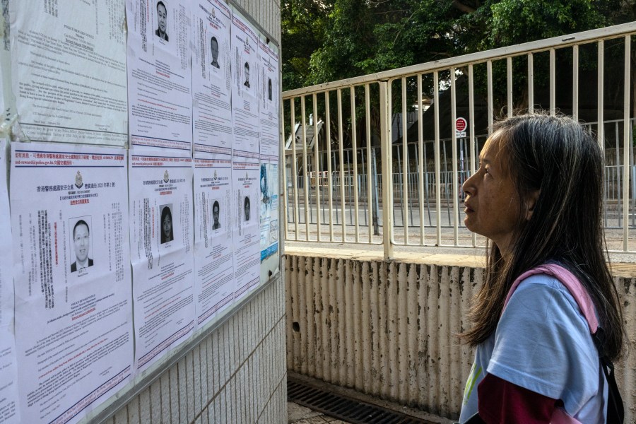 FILE - A pedestrian looks at the police reward notices for the arrest warrants issued for eight pro-democracy activists living in the United States, Britain, Canada and Australia for alleged national security offenses in Hong Kong, Friday, July 14, 2023. (AP Photo/Louise Delmotte, File)