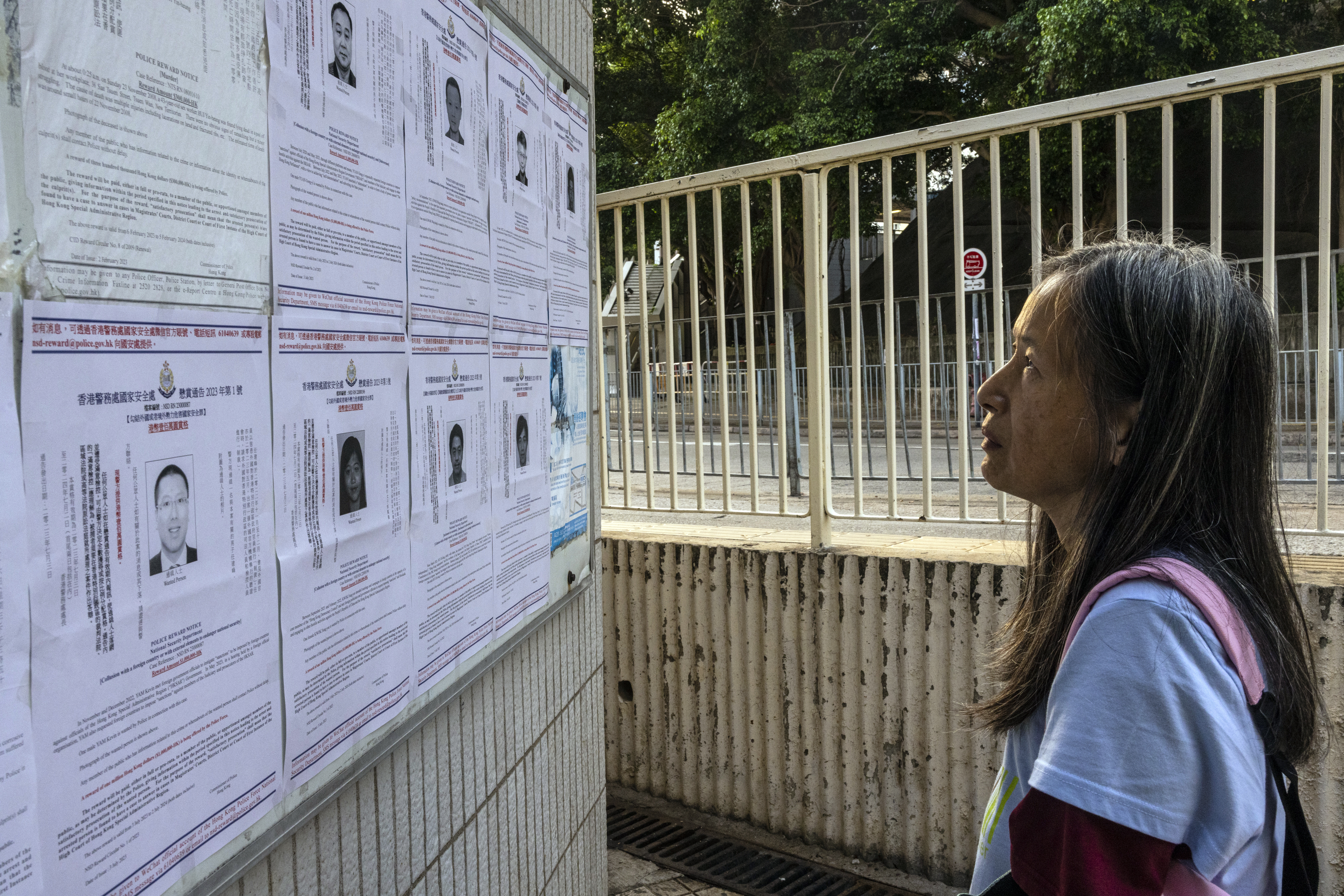 FILE - A pedestrian looks at the police reward notices for the arrest warrants issued for eight pro-democracy activists living in the United States, Britain, Canada and Australia for alleged national security offenses in Hong Kong, Friday, July 14, 2023. (AP Photo/Louise Delmotte, File)