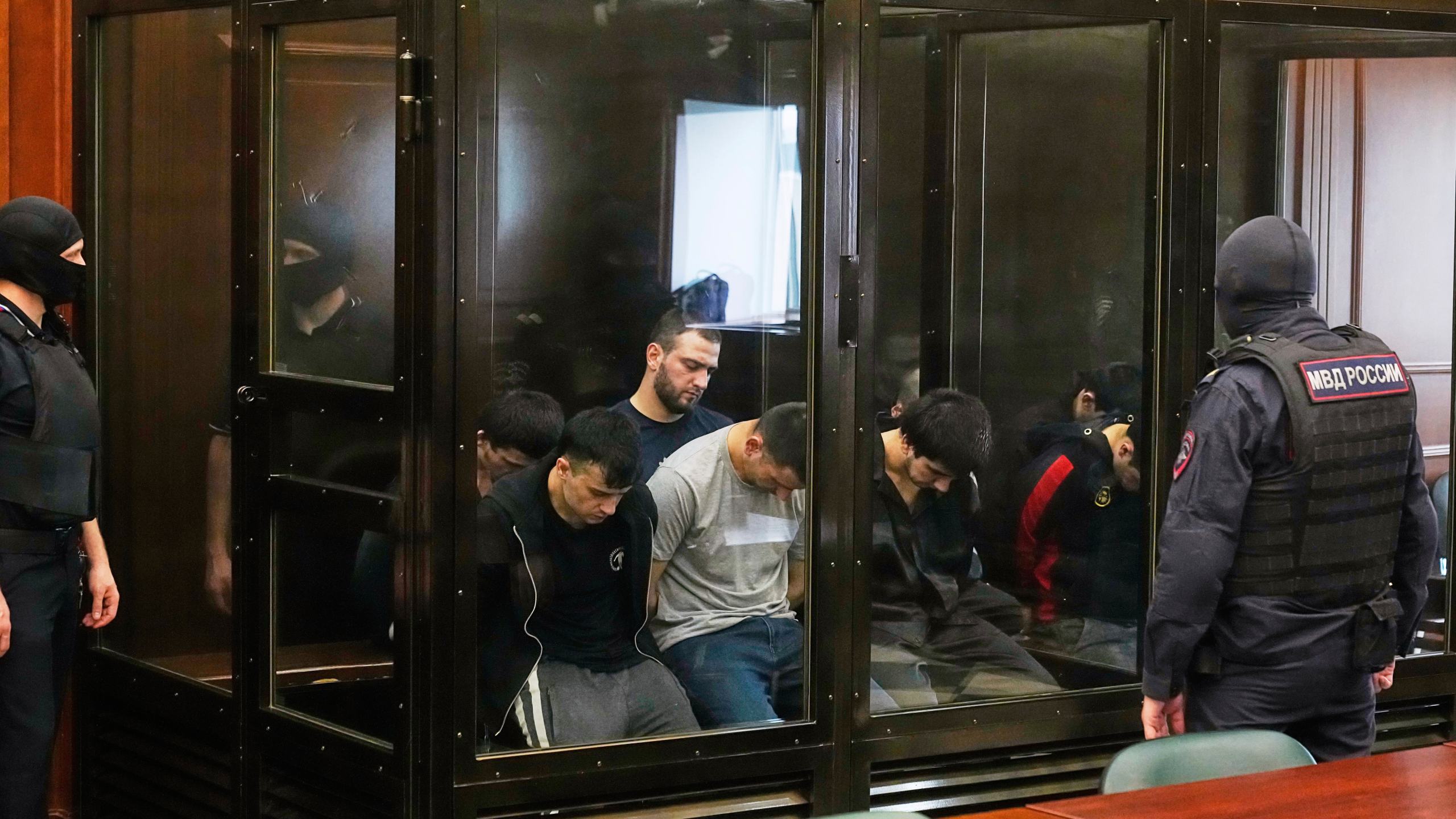 Suspects accused of involvement in a terror attack in the Crocus City Hall on March 22, 2024, sit in a glass cage prior to a hearing in the 2nd Western District Military Court in Moscow, Russia, Monday, Aug. 4, 2025. (AP Photo/Pavel Bednyakov)