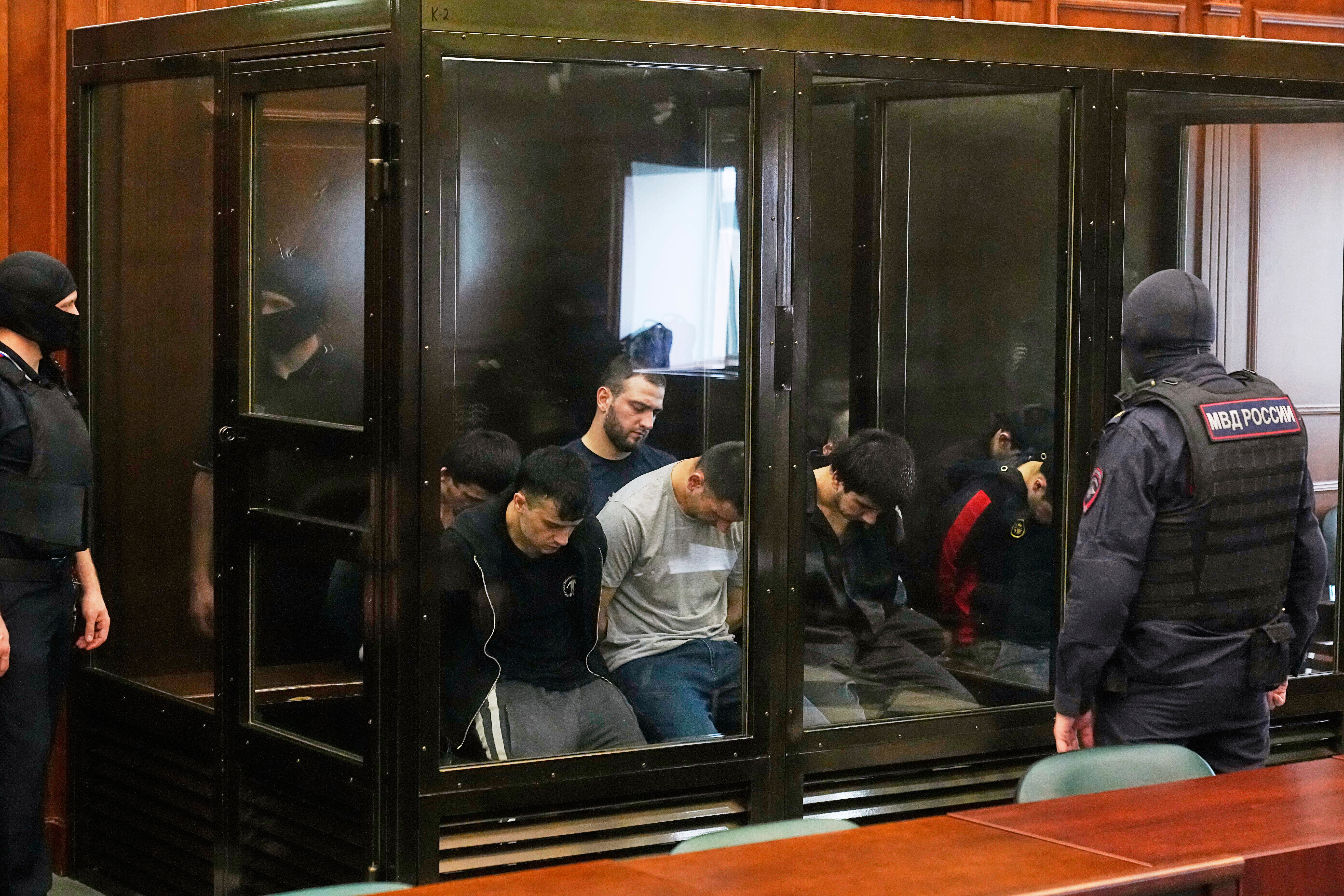 Suspects accused of involvement in a terror attack in the Crocus City Hall on March 22, 2024, sit in a glass cage prior to a hearing in the 2nd Western District Military Court in Moscow, Russia, Monday, Aug. 4, 2025. (AP Photo/Pavel Bednyakov)