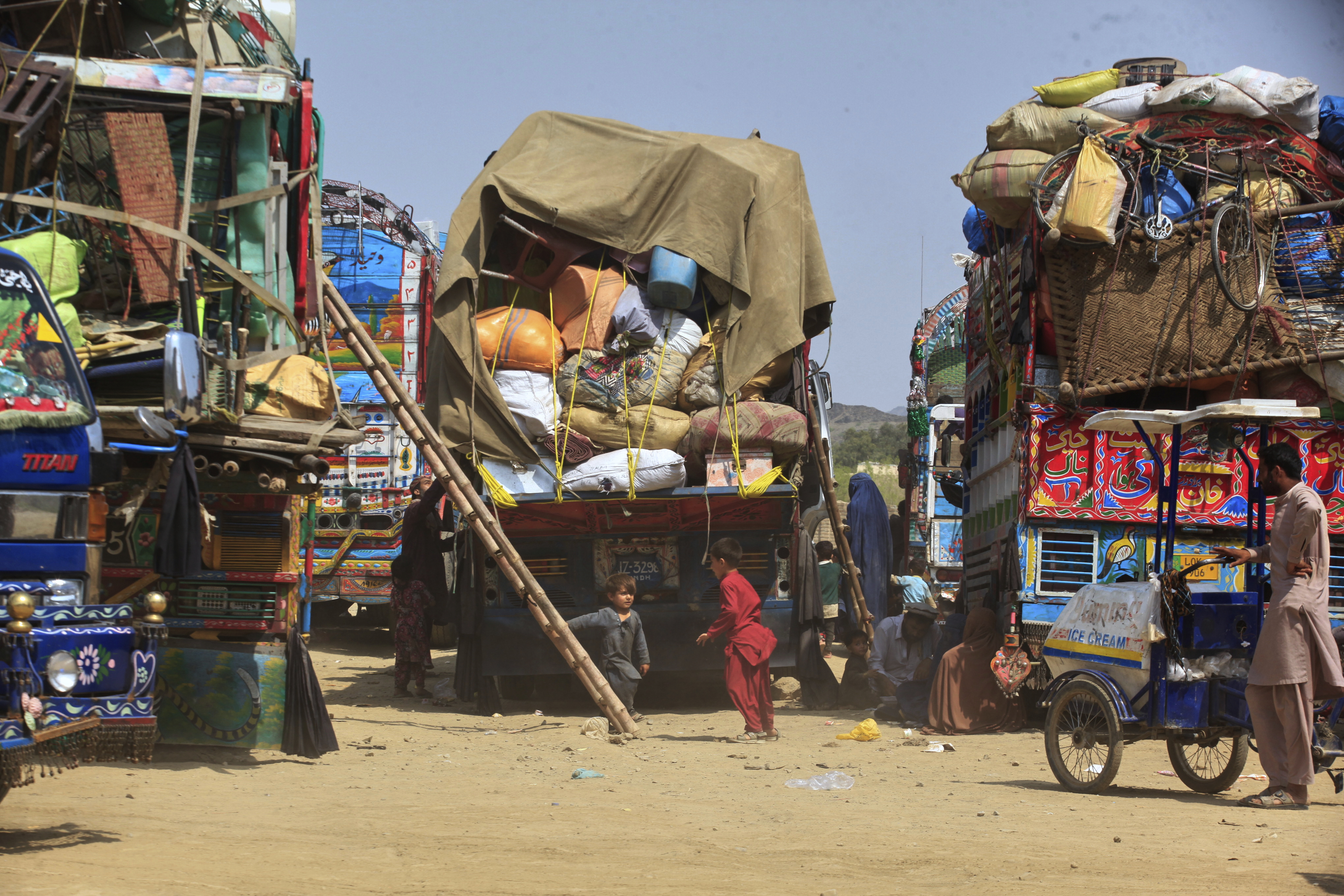 FILE - Afghan refugee children play next to trucks loaded with their family's belongings as they wait to return Afghanistan along a highway in Landi Kotal, Pakistan, April 9, 2025. (AP Photo/Muhammad Sajjad, File)