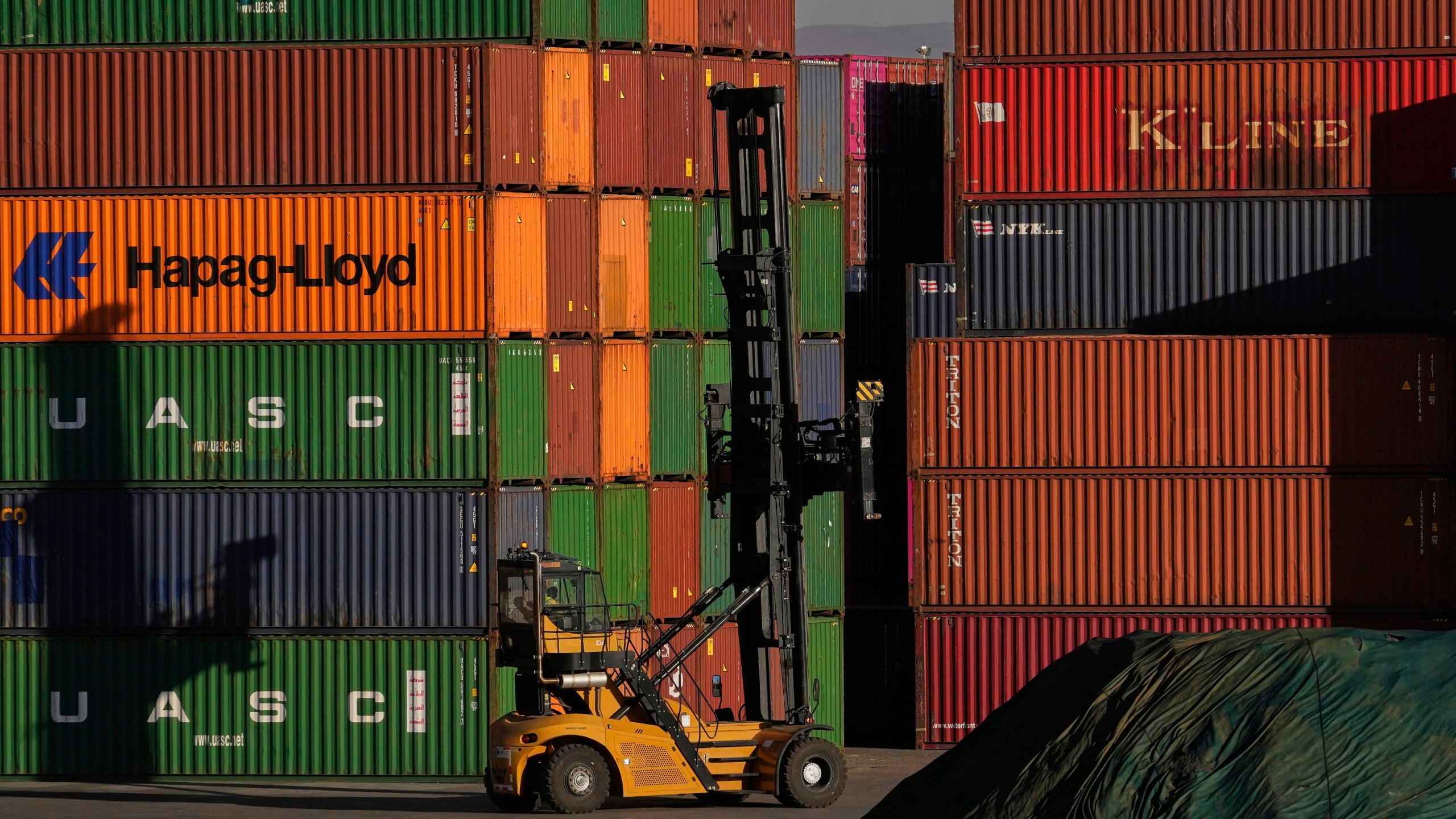 A heavy machine drives past shipping containers stacked at a depo, in Johannesburg, South Africa, Friday, Aug. 1, 2025. (AP Photo/Themba Hadebe)