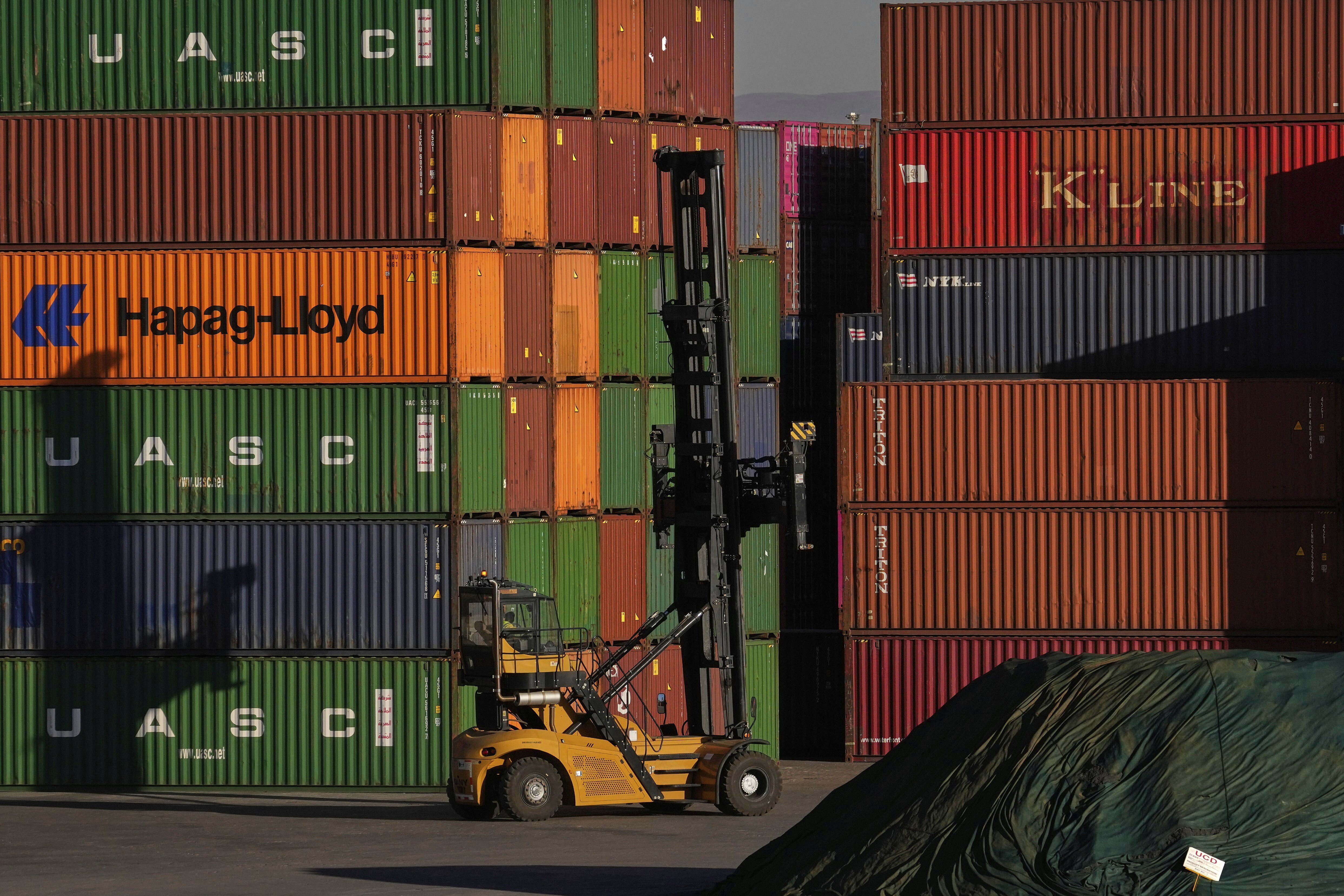 A heavy machine drives past shipping containers stacked at a depo, in Johannesburg, South Africa, Friday, Aug. 1, 2025. (AP Photo/Themba Hadebe)