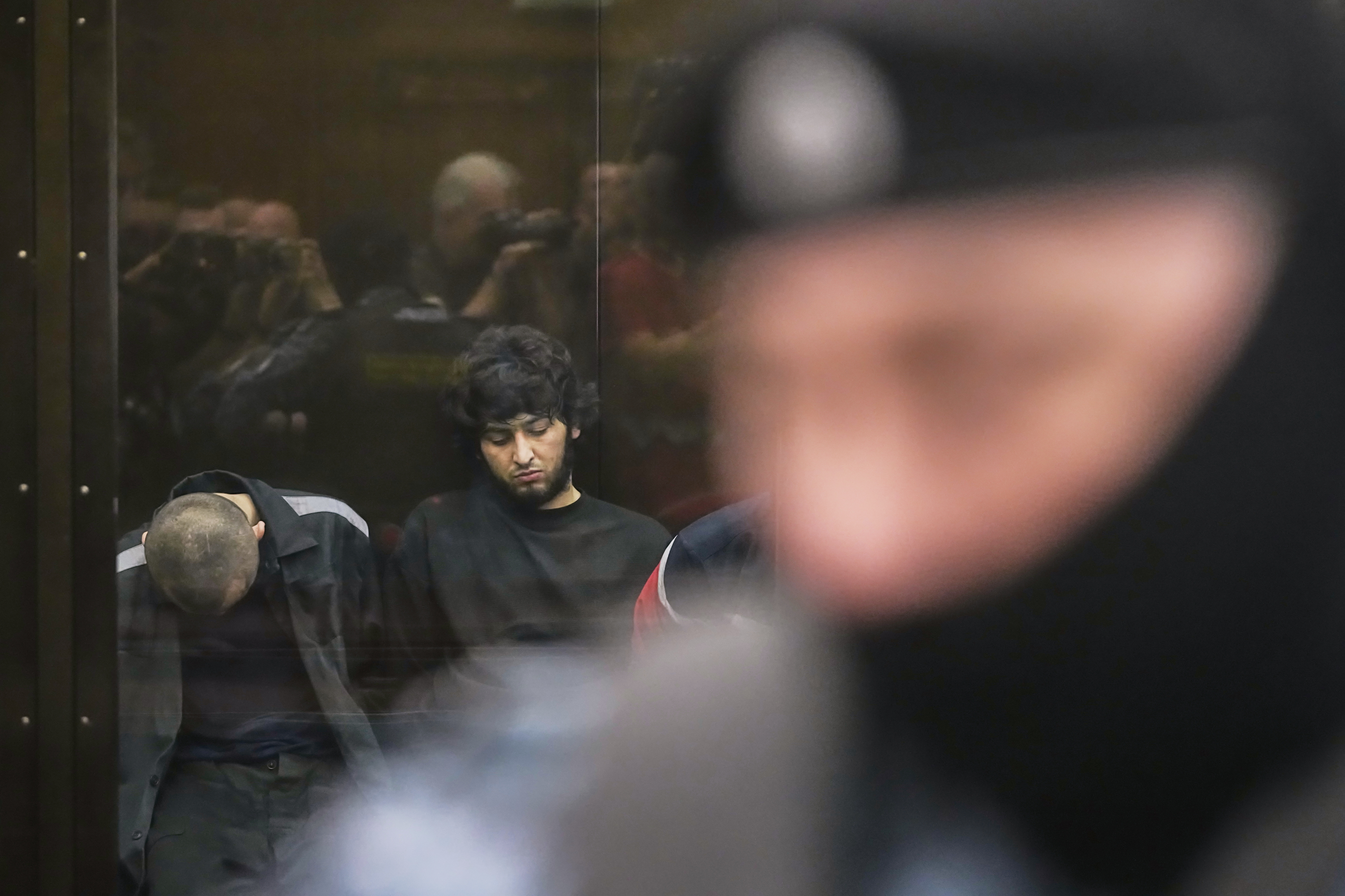 Suspects accused of involvement in a terror attack in the Crocus City Hall on March 22, 2024, sit in a glass cage prior to a hearing in the 2nd Western District Military Court in Moscow, Russia, Monday, Aug. 4, 2025. (AP Photo/Pavel Bednyakov)