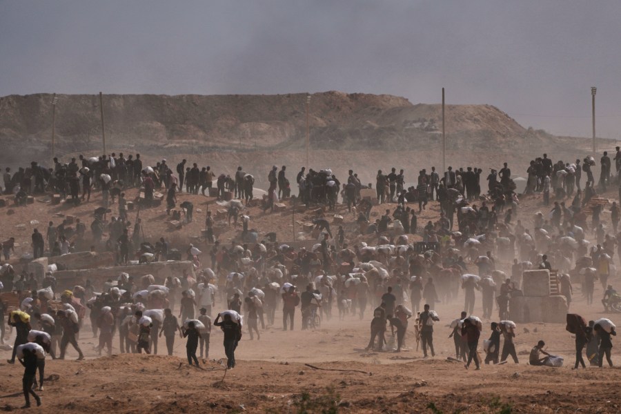 Palestinians carry humanitarian aid packages near a Gaza Humanitarian Foundation distribution center operated by the U.S.-backed organization, in Netzarim, central Gaza Strip, Monday, Aug. 4, 2025. (AP Photo/Abdel Kareem Hana)