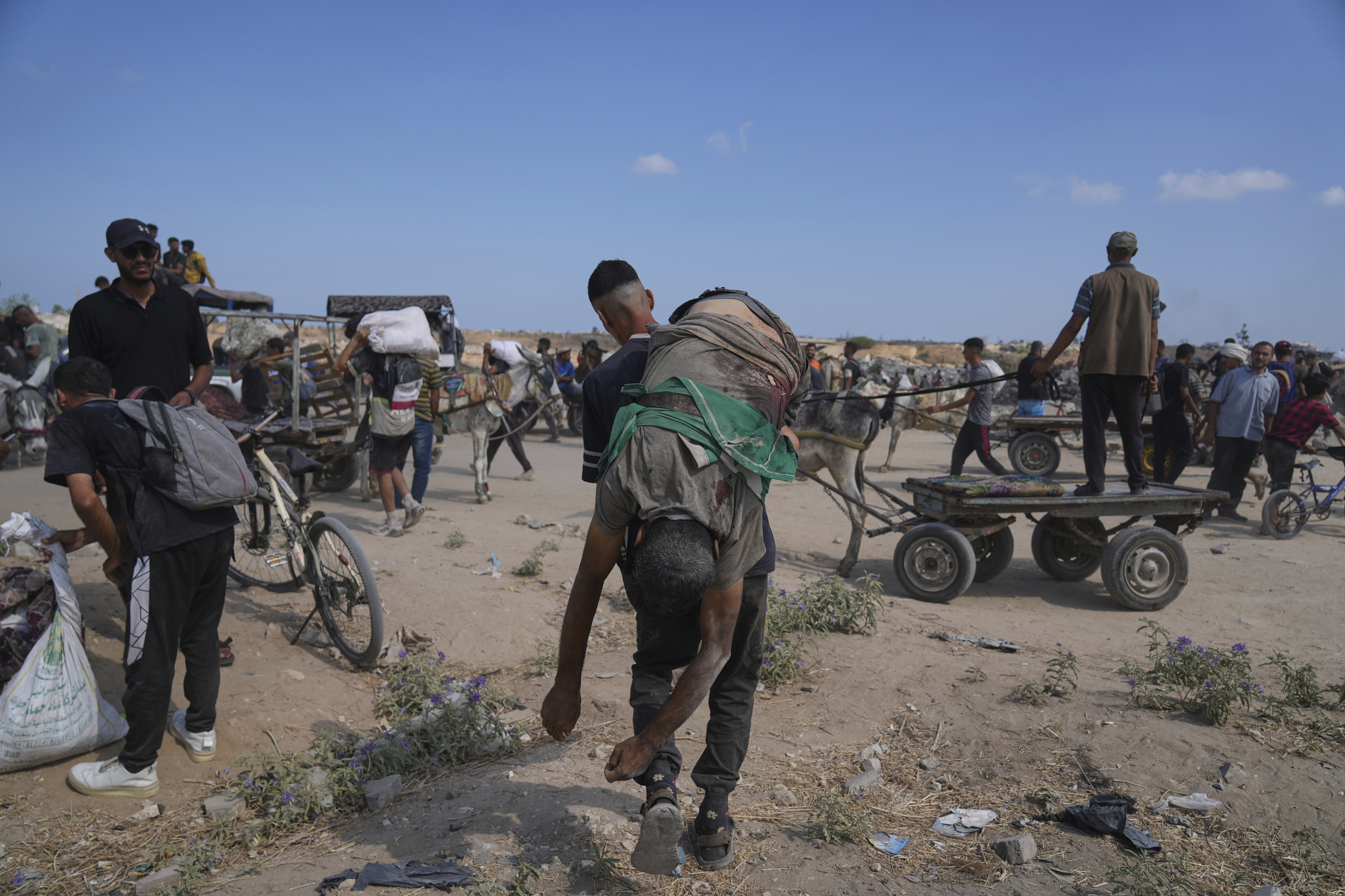 A Palestinian carries the body of a man killed while trying to receive aid near a distribution center operated by the U.S.-backed Gaza Humanitarian Foundation (GHF) in Netzarim, in the Gaza Strip, Monday, Aug. 4, 2025. (AP Photo/Abdel Kareem Hana)