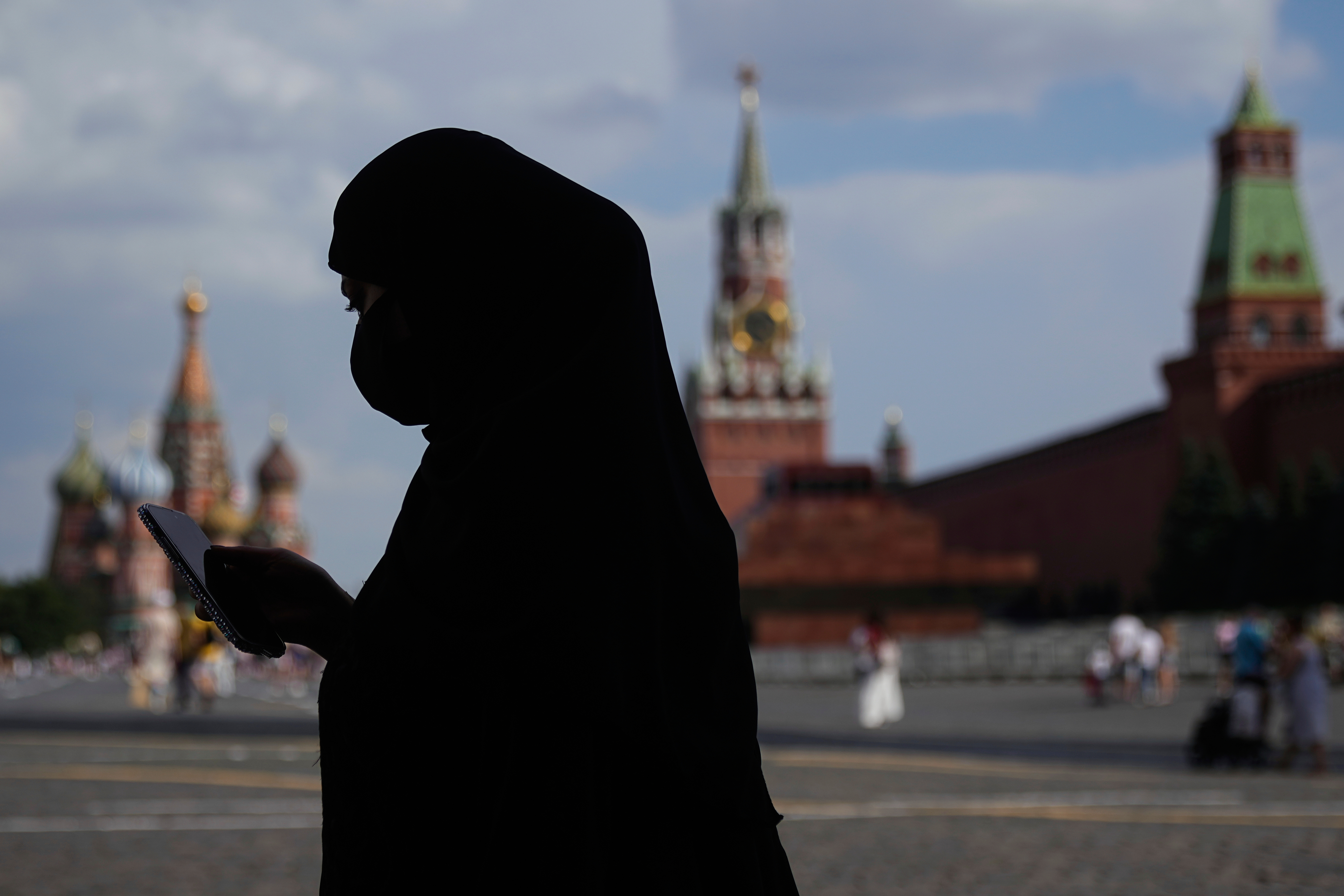 A woman wearing a niqab, checks her phone while walking along the Red Square in Moscow, Russia, Wednesday, July 30, 2025. (AP Photo/Pavel Bednyakov)