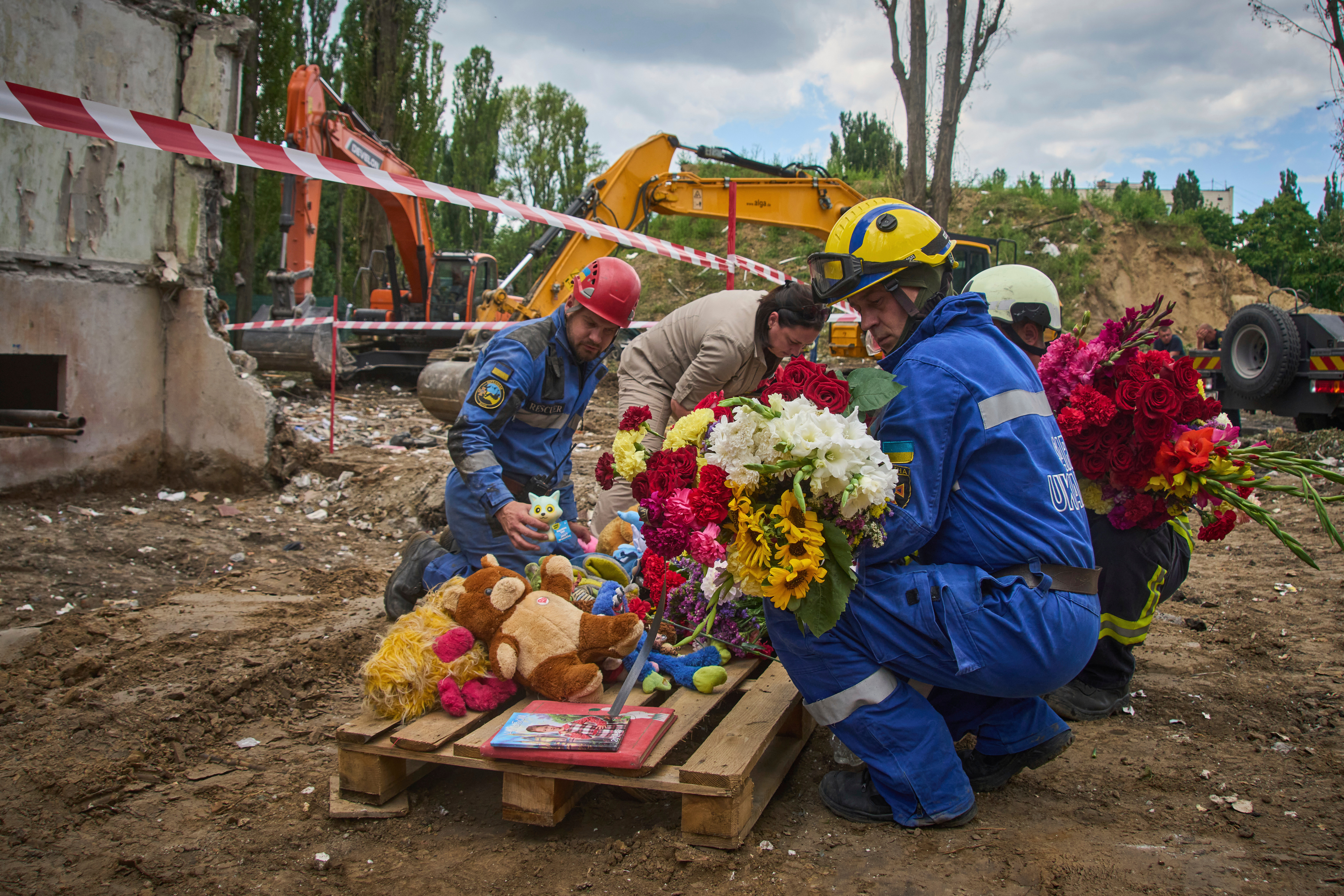 Rescuers lay toys and flowers on the site of Russia's Thursday night missile strike that hit a multistory residential house killing 31 civilians including five children in Kyiv, Ukraine, Friday, Aug. 1, 2025. (AP Photo/Efrem Lukatsky)