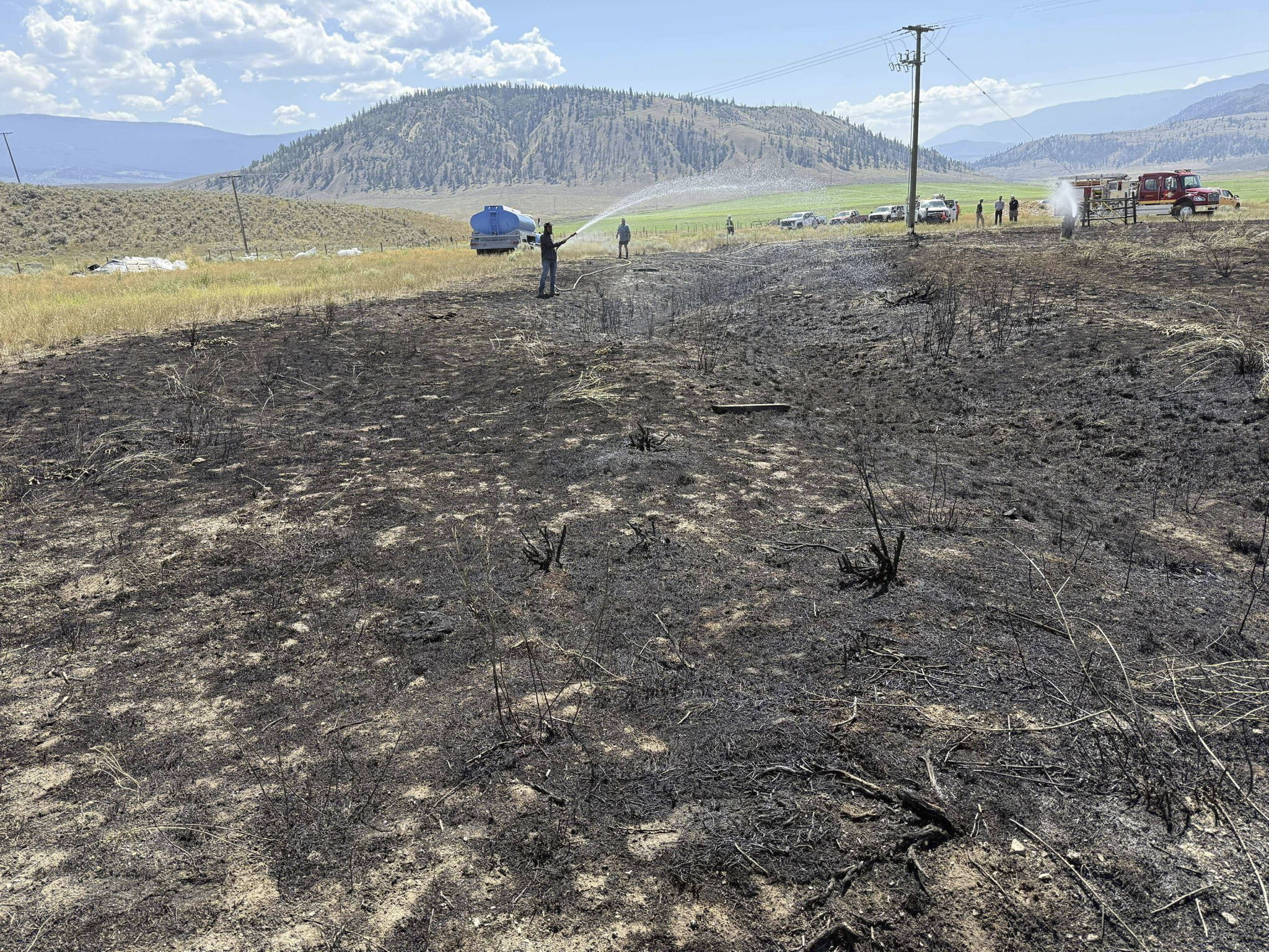 This image provided by the Ashcroft Fire Rescue shows people putting out a brush fire south of Ashcroft, British Columbia, on Wednesday, July 30, 2025. (Ashcroft Fire Rescue/Canadian Press via AP)