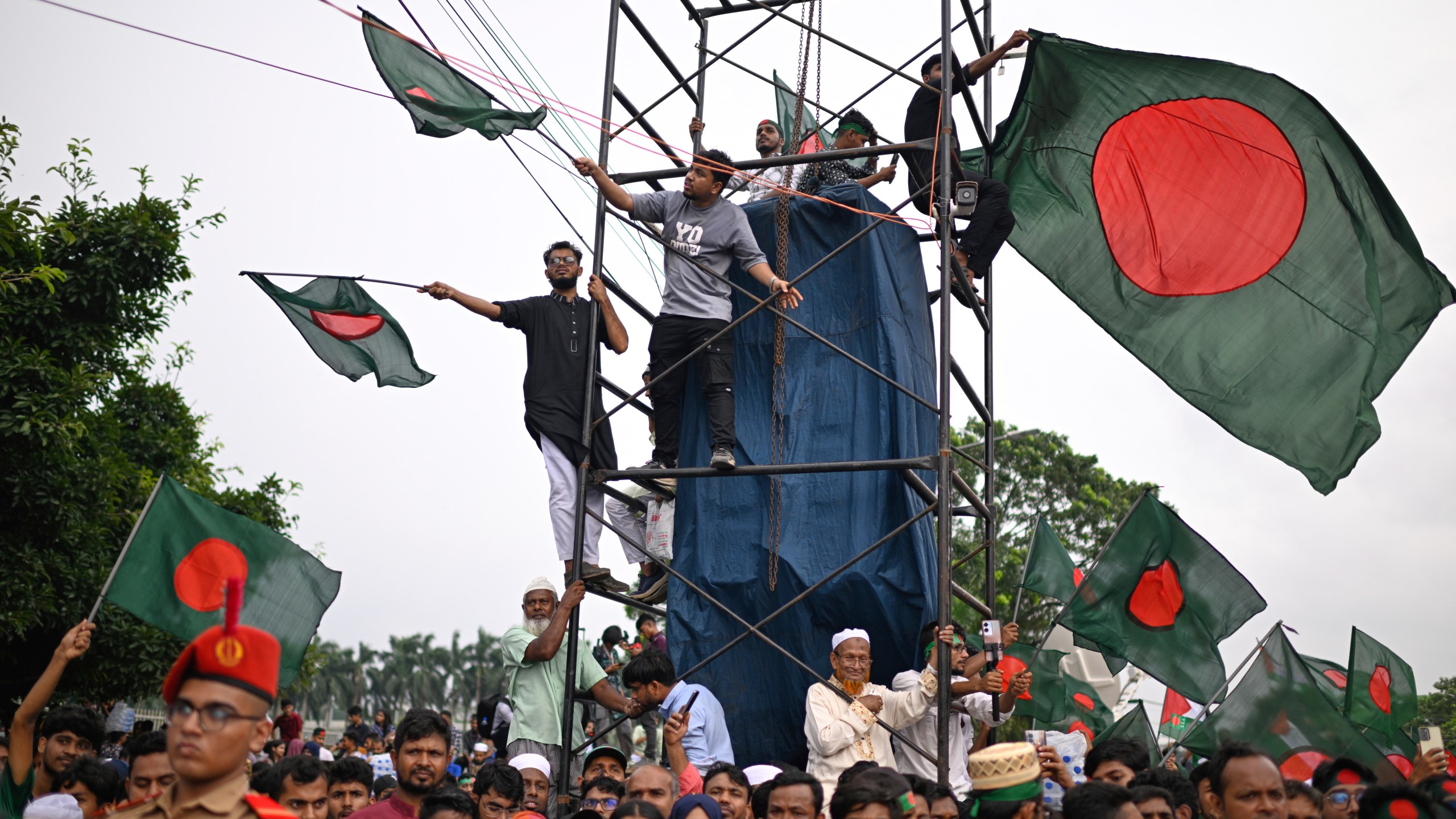 People wave national flags as they gather to commemorate "July Uprising Day" marking the anniversary of the fall of the Awami League government, in Dhaka, Bangladesh, Tuesday, Aug. 5, 2025. (AP Photo/Mahmud Hossain Opu)