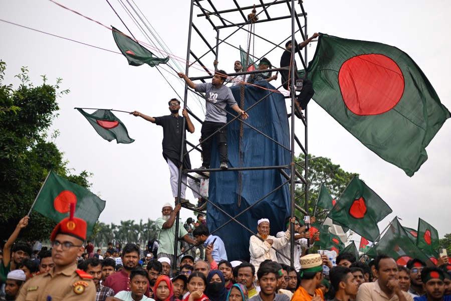 People wave national flags as they gather to commemorate "July Uprising Day" marking the anniversary of the fall of the Awami League government, in Dhaka, Bangladesh, Tuesday, Aug. 5, 2025. (AP Photo/Mahmud Hossain Opu)