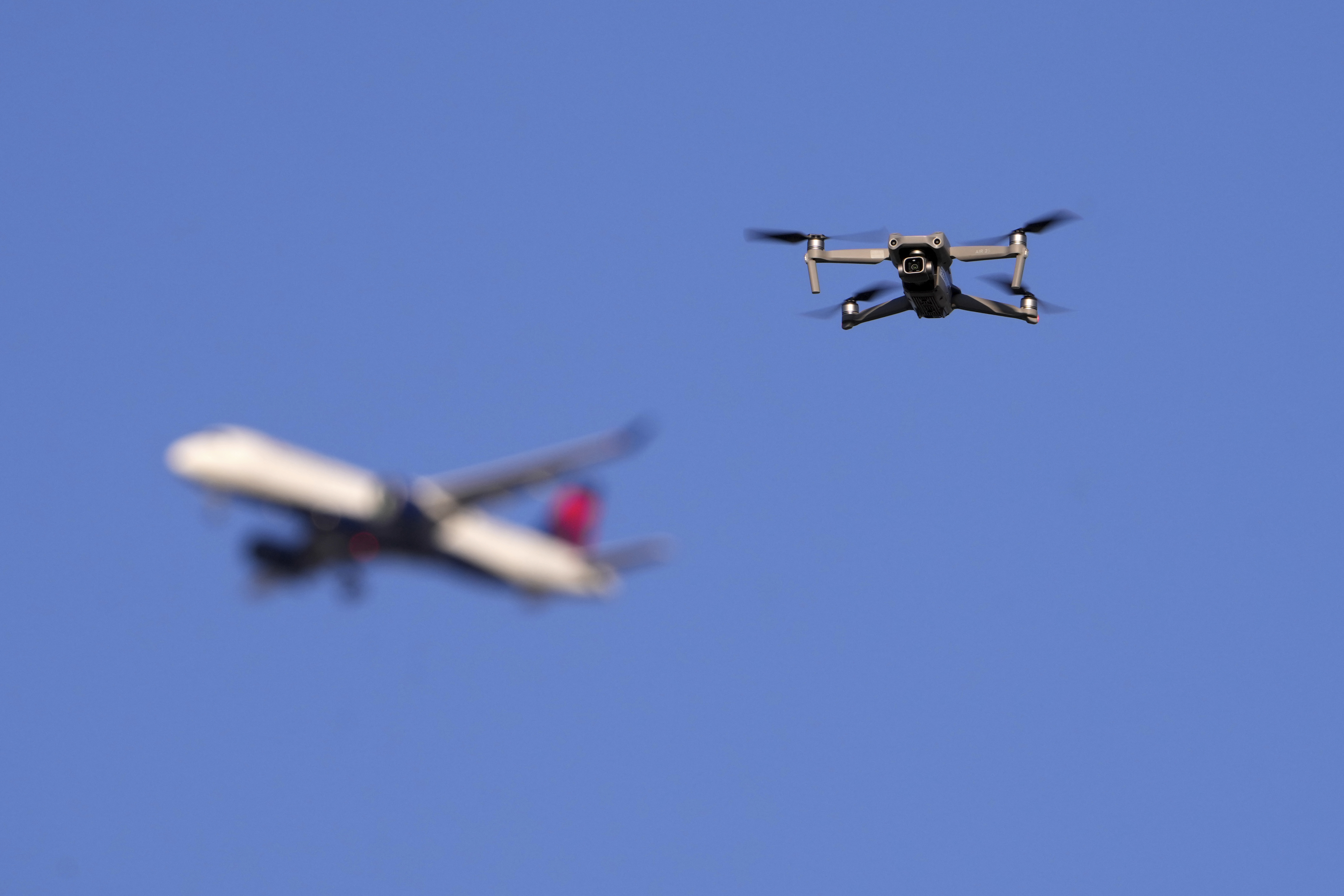 FILE - A drone hovers in airspace outside the safety perimeter surrounding St. Louis Lambert International Airport as an airliner approaches for a landing on March 10, 2025. (AP Photo/Jeff Roberson, File)