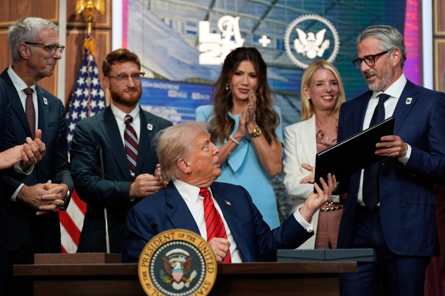 President Donald Trump hands a signed executive order about the 2028 Los Angeles Olympic Games, to Casey Wasserman, chairman of LA28, in the South Court Auditorium of the Eisenhower Executive Office Building on the White House campus, Tuesday, Aug. 5, 2025, in Washington. (AP Photo/Alex Brandon)