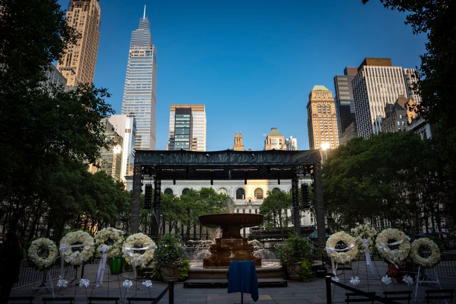 Flower wreaths with the words "Rest In Peace" stand at a vigil for the four people killed in the previous day's shooting at 345 Park Avenue, including NYPD officer Didarul Islam, in Bryant Park, Tuesday, July 29, 2025, in New York. (AP Photo/Angelina Katsanis)