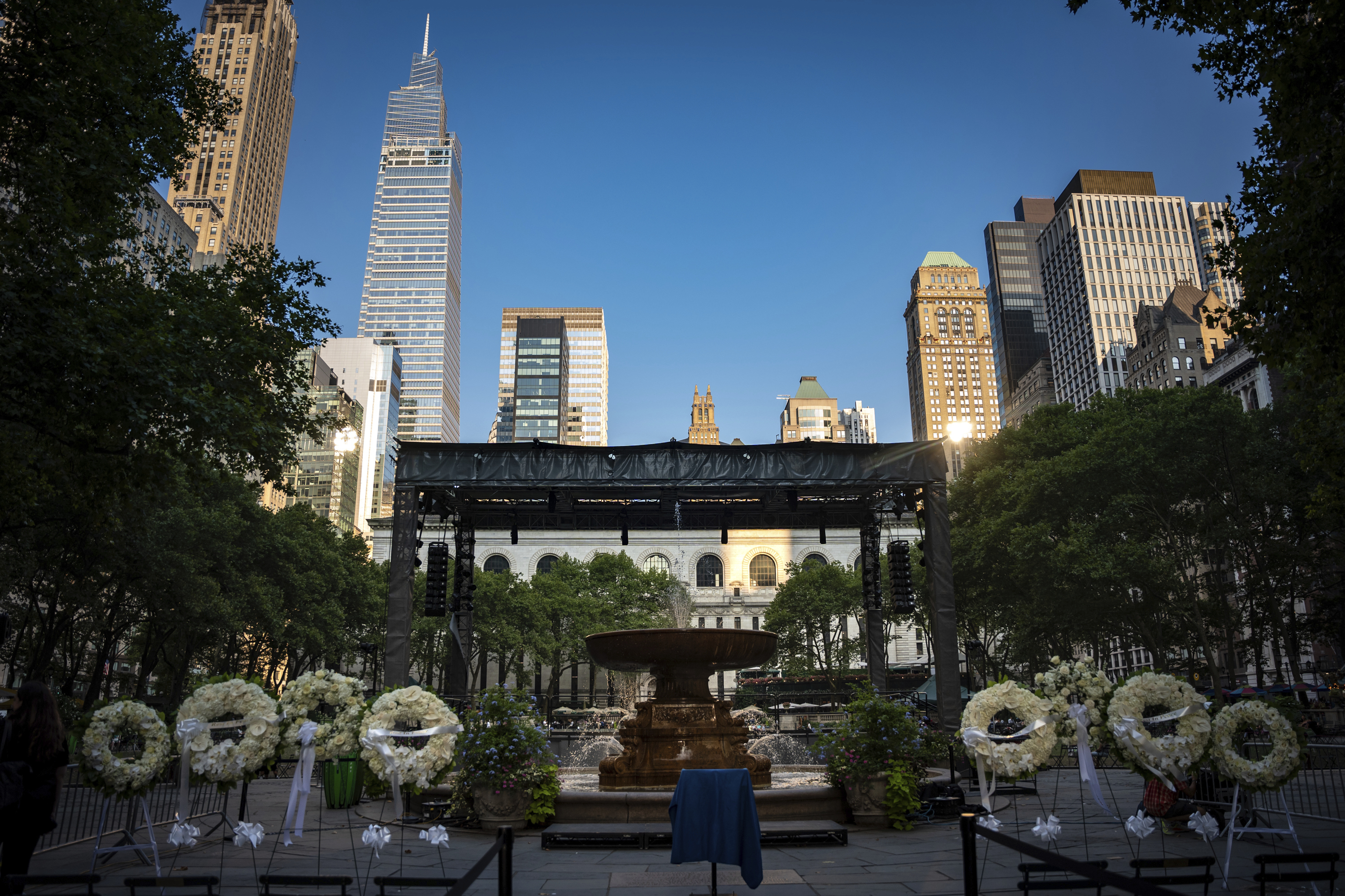 Flower wreaths with the words "Rest In Peace" stand at a vigil for the four people killed in the previous day's shooting at 345 Park Avenue, including NYPD officer Didarul Islam, in Bryant Park, Tuesday, July 29, 2025, in New York. (AP Photo/Angelina Katsanis)
