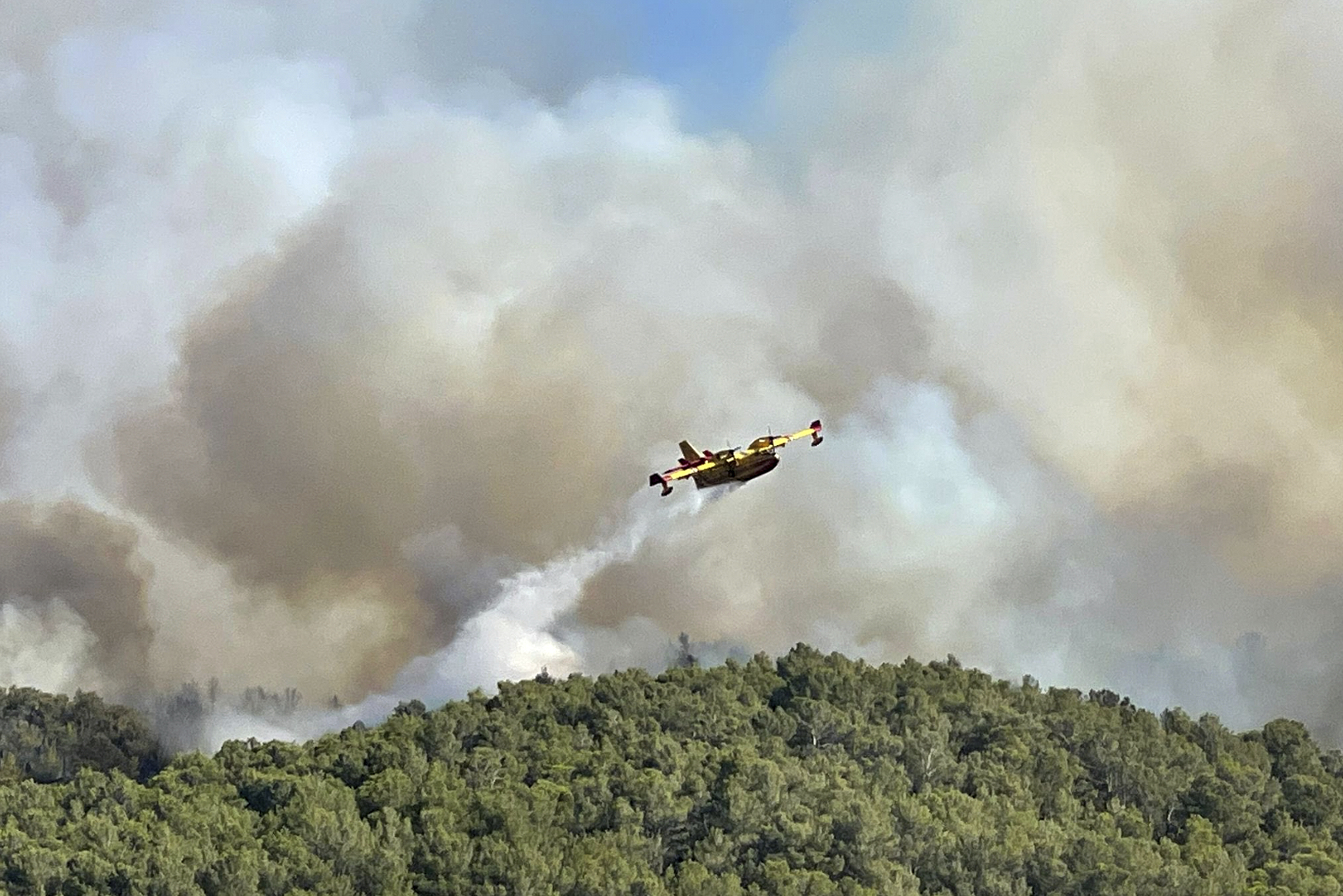This photo provided by the Securite Civile shows a water bomber plane dropping water on the wildfire in the Corbieres massif , southern France, Tuesday, Aug. 5, 2025. (Securite Civile via AP)