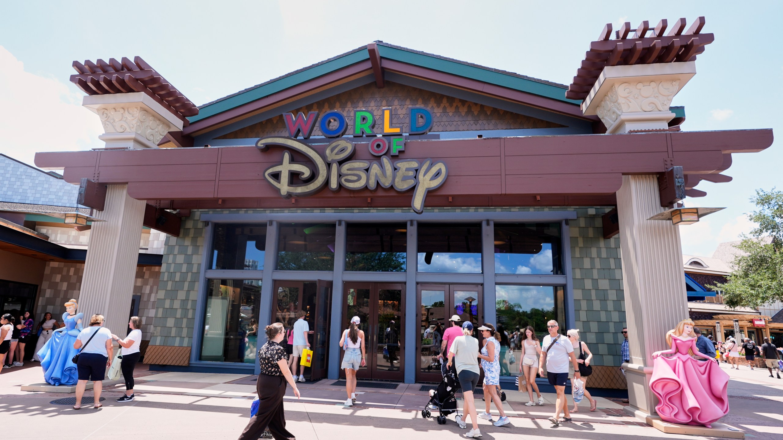 Tourists stroll by the World of Disney store at Disney Springs shopping and entertainment district Tuesday, Aug. 5, 2025, in Lake Buena Vista, Fla. (AP Photo/John Raoux)