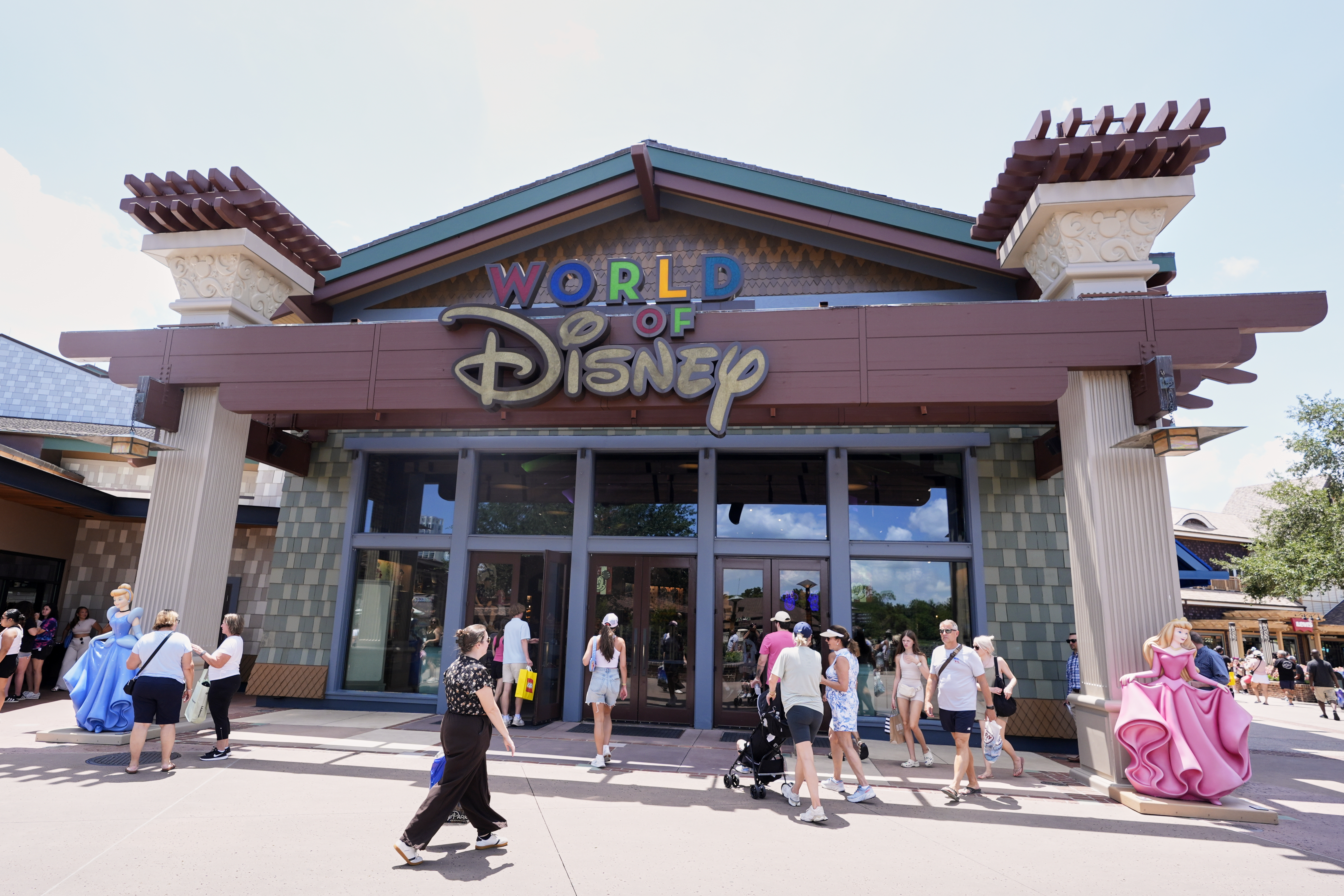Tourists stroll by the World of Disney store at Disney Springs shopping and entertainment district Tuesday, Aug. 5, 2025, in Lake Buena Vista, Fla. (AP Photo/John Raoux)