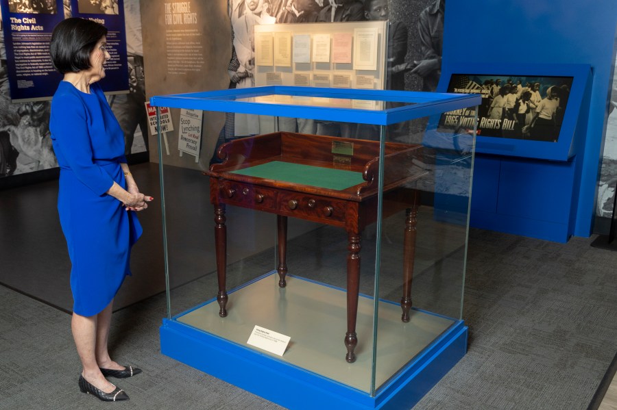FILE - Luci Baines Johnson looks at the desk May 16, 2023, on display at the LBJ Presidential Library, that President Lyndon B. Johnson sat at in the President's Room at the U.S. Capitol to sign the Voting Rights Act of 1965, on Aug. 6, 1965. (AP Photo/Stephen Spillman, File)