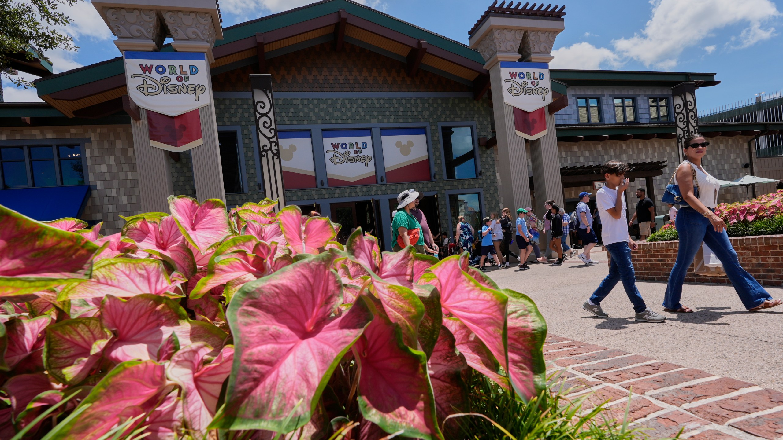 Tourists stroll by the World of Disney store at Disney Springs shopping and entertainment district Tuesday, Aug. 5, 2025, in Lake Buena Vista, Fla. (AP Photo/John Raoux)