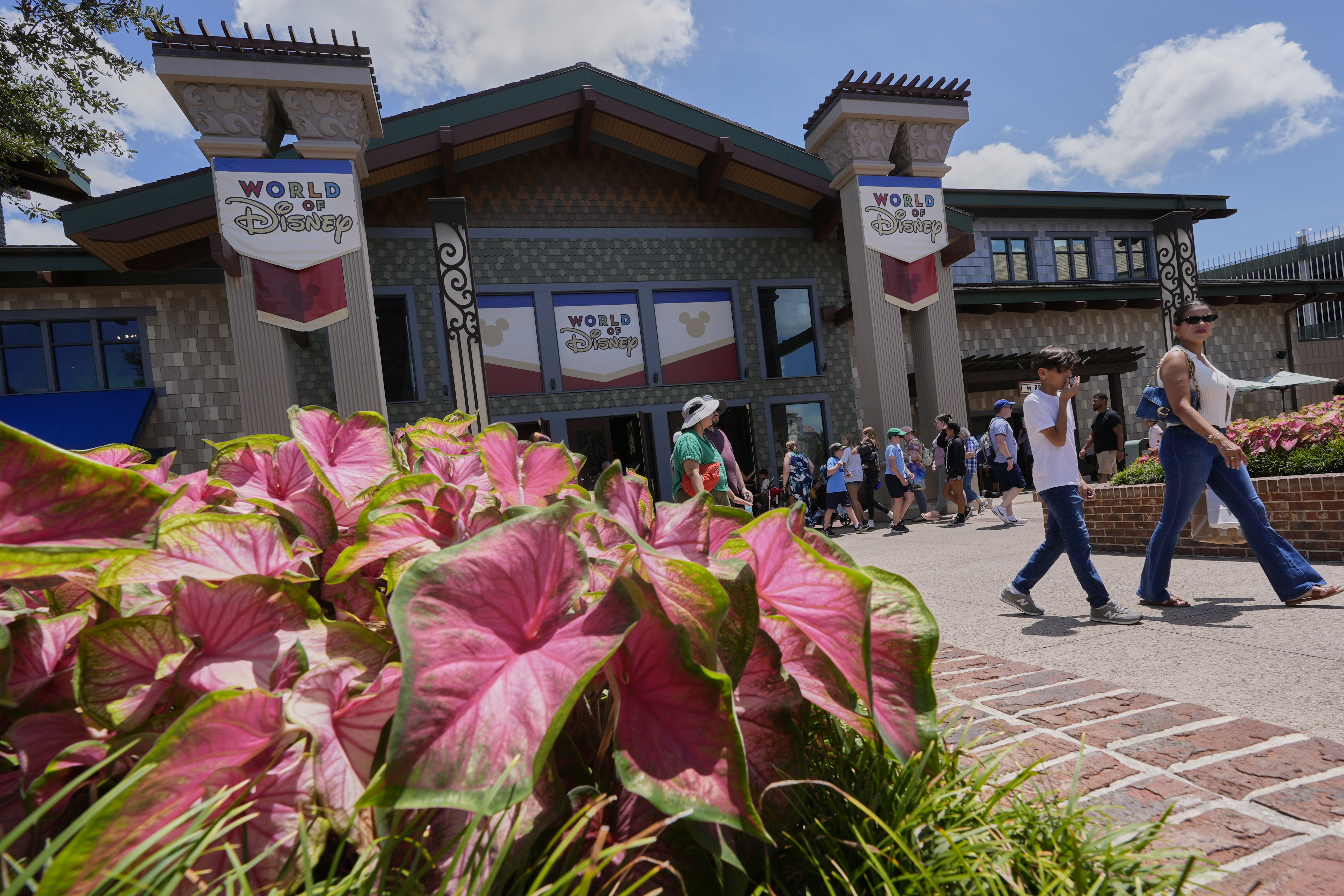 Tourists stroll by the World of Disney store at Disney Springs shopping and entertainment district Tuesday, Aug. 5, 2025, in Lake Buena Vista, Fla. (AP Photo/John Raoux)