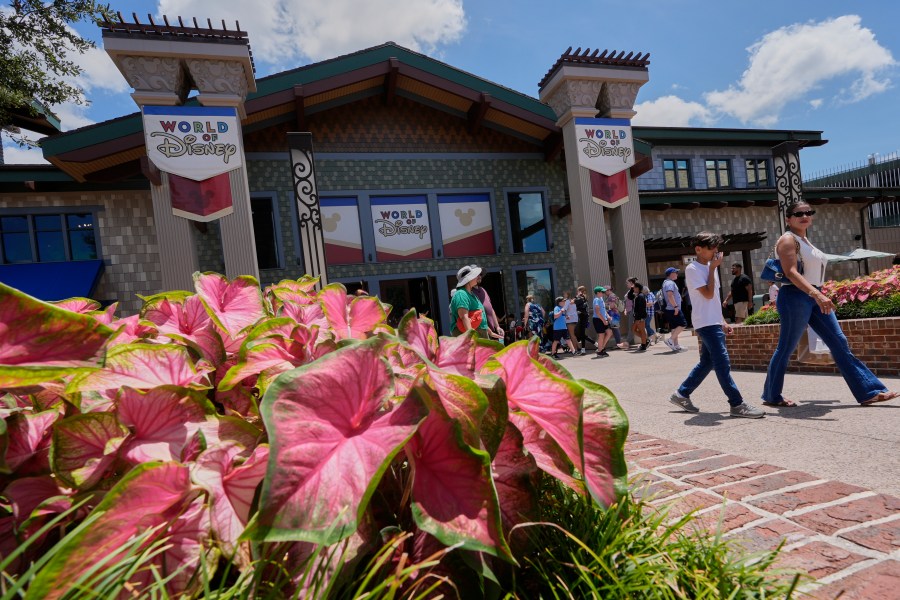 Tourists stroll by the World of Disney store at Disney Springs shopping and entertainment district Tuesday, Aug. 5, 2025, in Lake Buena Vista, Fla. (AP Photo/John Raoux)