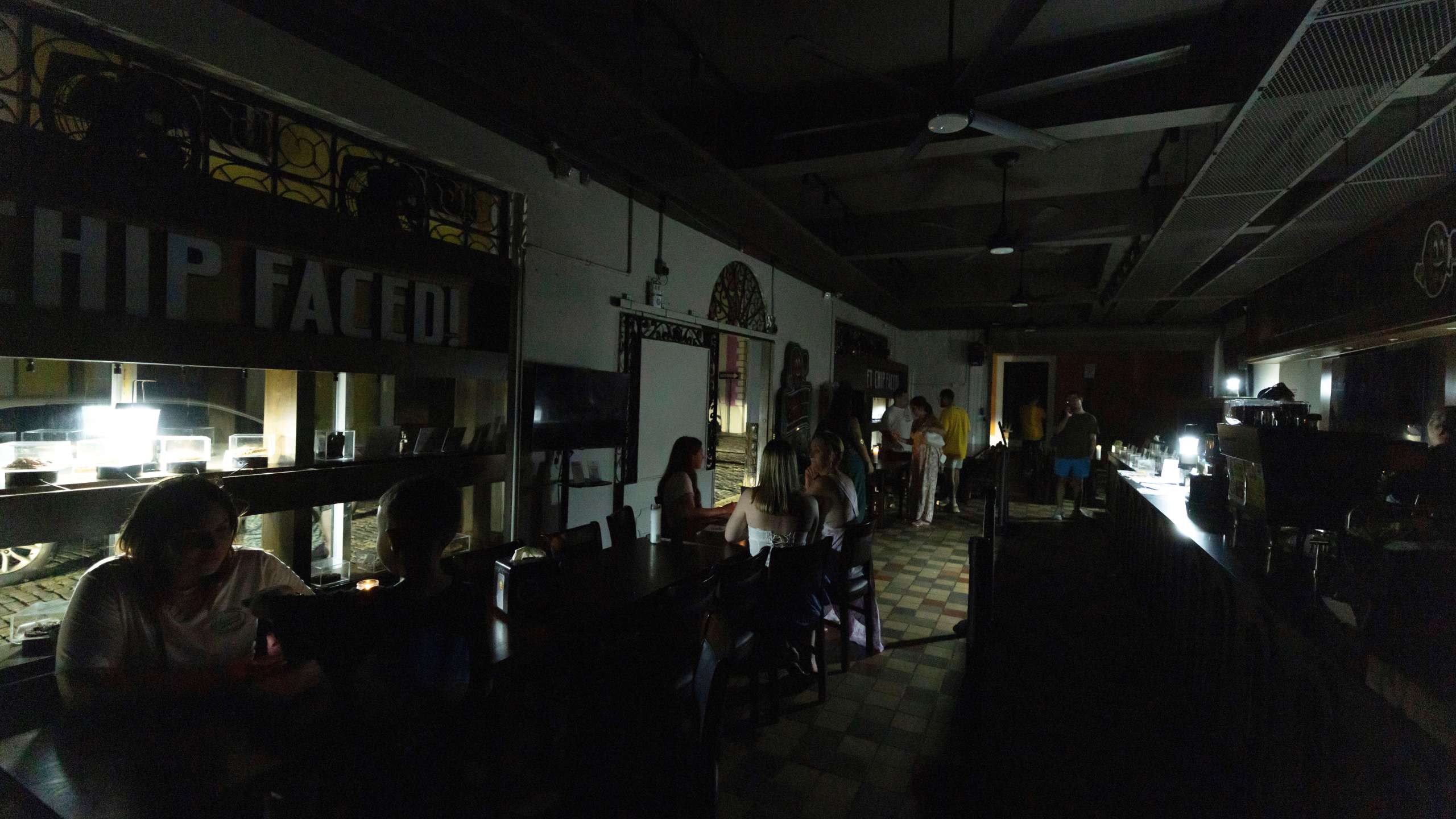FILE - Customers sit inside a restaurant lit by battery-powered lanterns during an island-wide power outage, in Old San Juan, Puerto Rico, April 16, 2025. (AP Photo/Alejandro Granadillo, File)