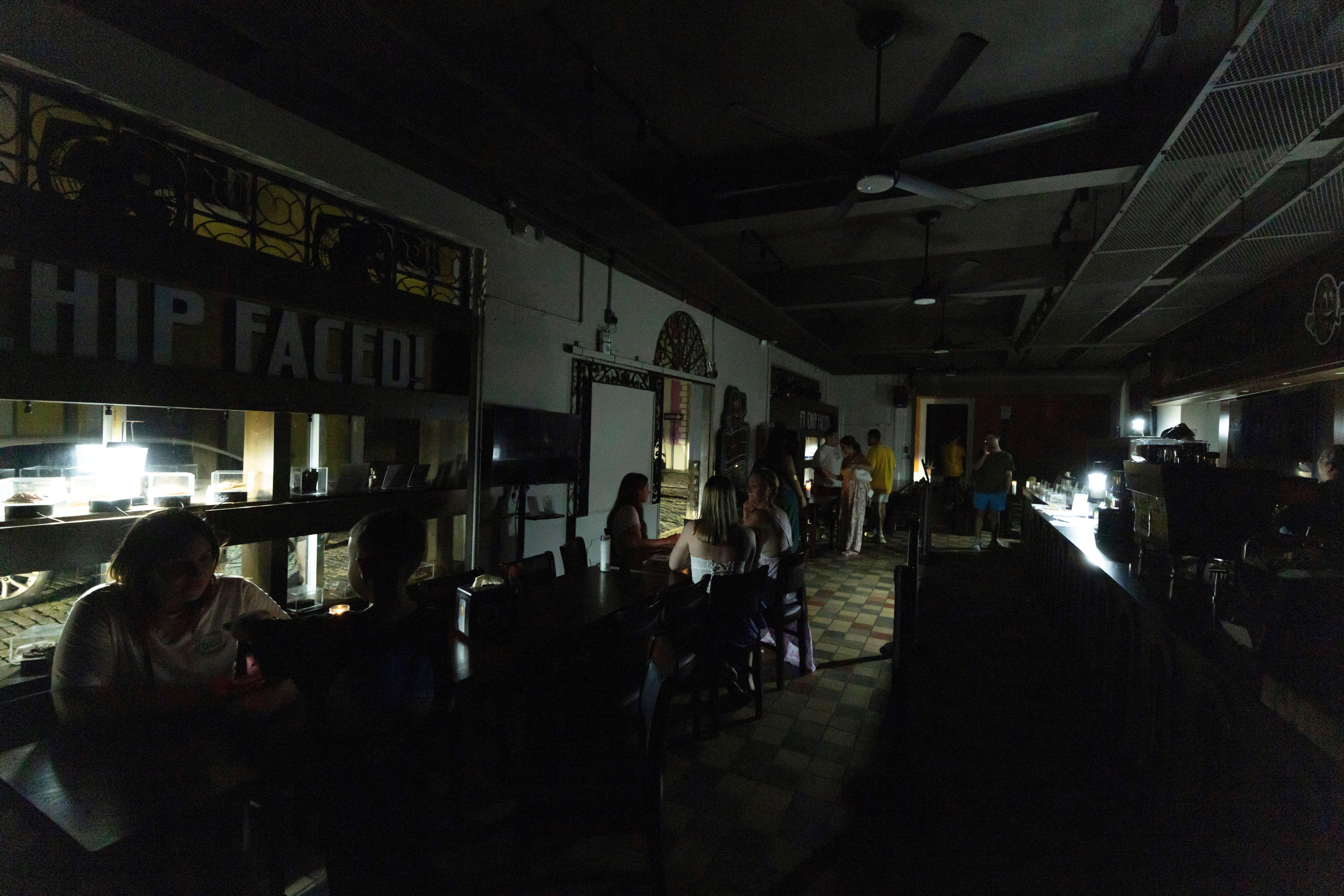 FILE - Customers sit inside a restaurant lit by battery-powered lanterns during an island-wide power outage, in Old San Juan, Puerto Rico, April 16, 2025. (AP Photo/Alejandro Granadillo, File)