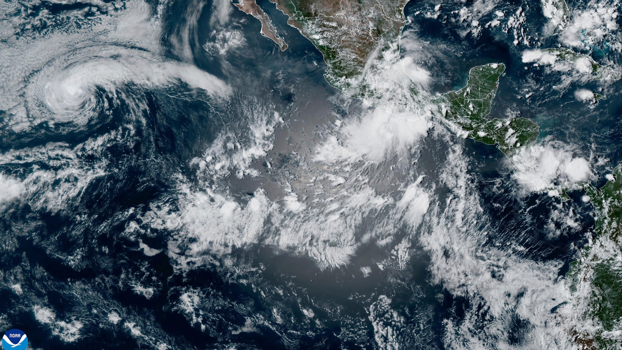 This satellite image from the National Oceanic and Atmospheric Administration taken at 5:20pm ET shows Tropical Storm Henriette, left, and Tropical Storm Ivo, center right, off the coast of southern Mexico in the eastern Pacific Ocean, on Wednesday, Aug. 6, 2025. (NOAA via AP)