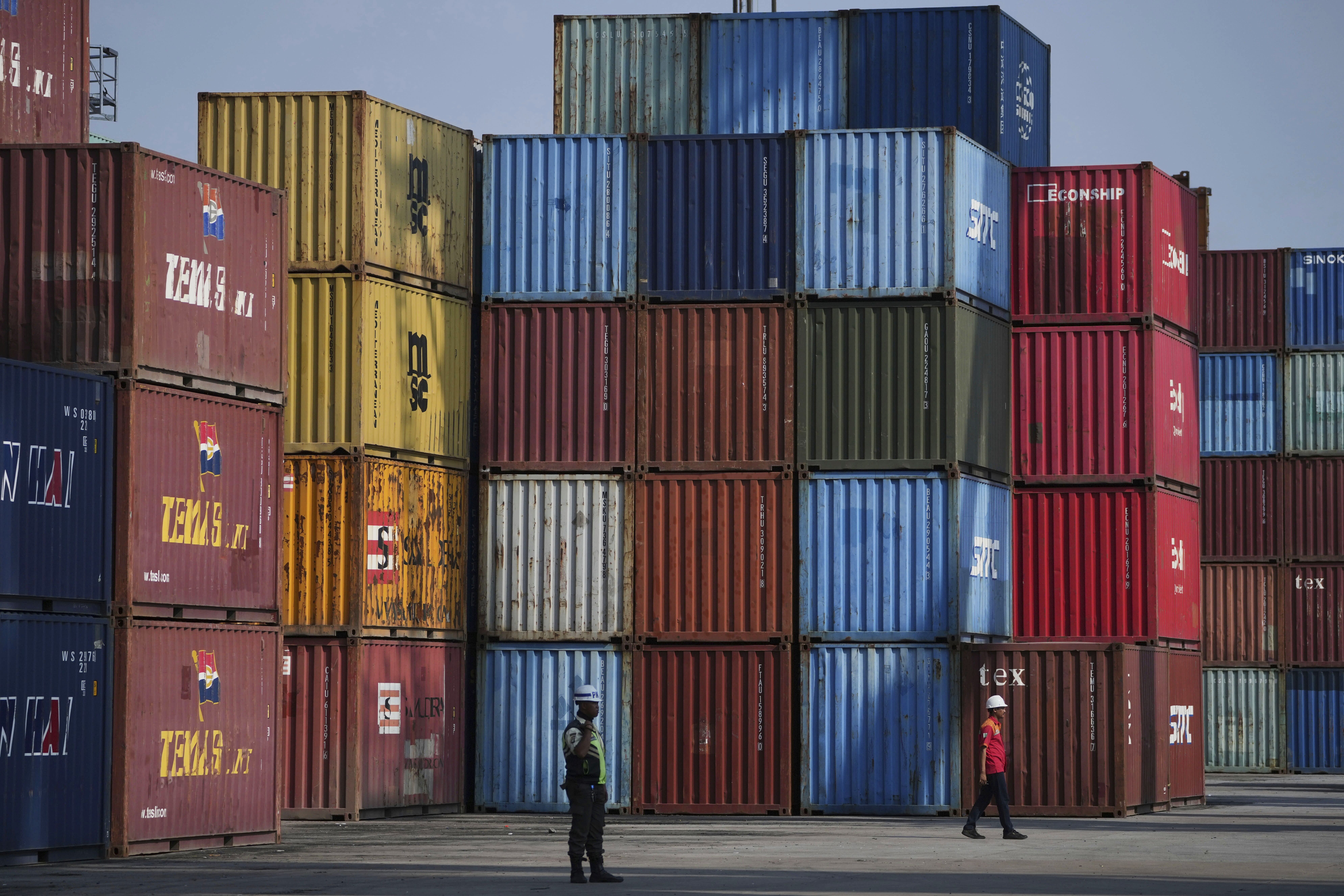 A worker walks near shipping containers at IPC Container Terminal at Tanjung Priok Port in Jakarta, Indonesia, Wednesday, Aug. 6, 2025. (AP Photo/Achmad Ibrahim)