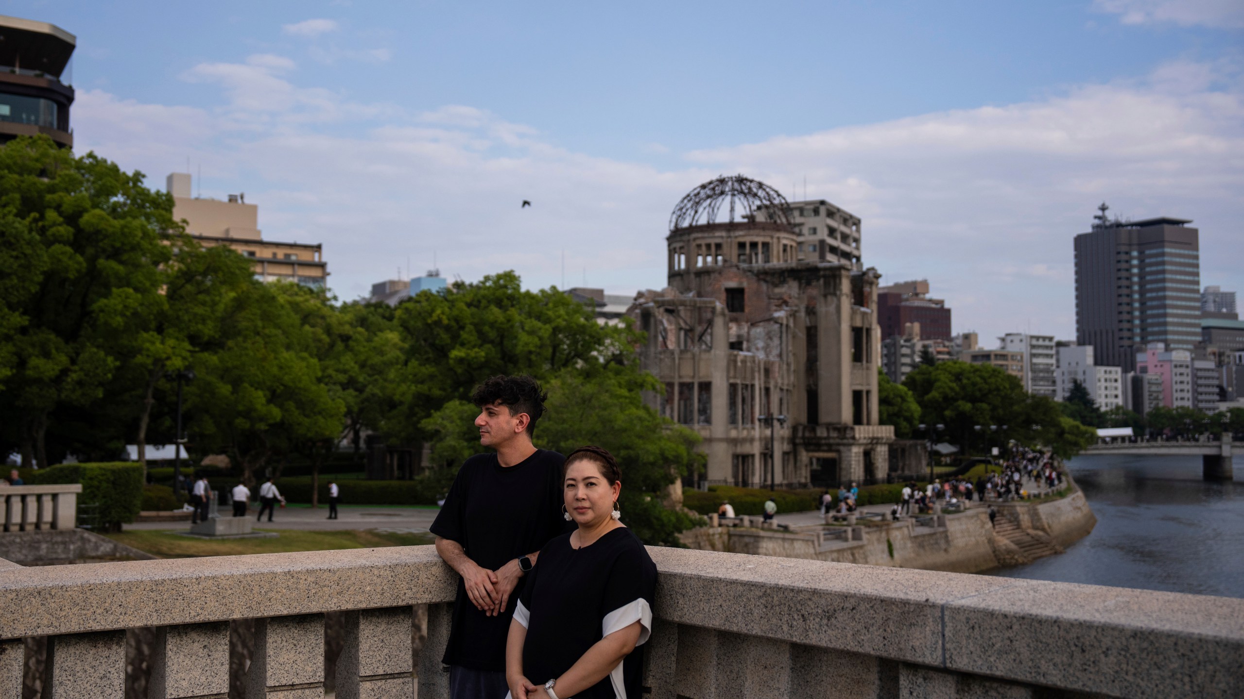 Ari Beser, left, and Kosuzu Harada, right, pose for photographs after an interview with The Associated Press in front of the Atomic Bomb Dome in Hiroshima, western Japan Tuesday, Aug. 5, 2025. (AP Photo/Louise Delmotte)