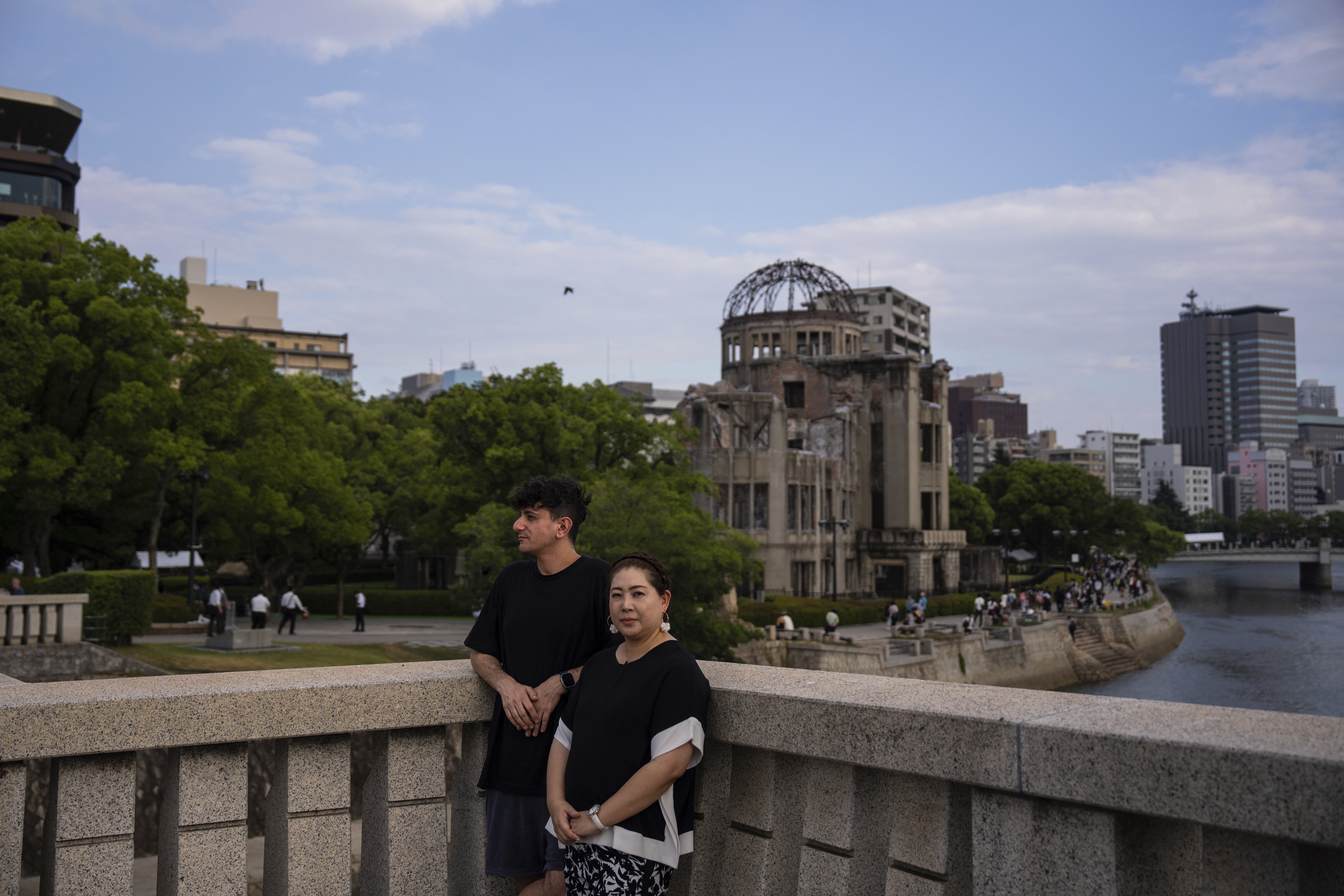 Ari Beser, left, and Kosuzu Harada, right, pose for photographs after an interview with The Associated Press in front of the Atomic Bomb Dome in Hiroshima, western Japan Tuesday, Aug. 5, 2025. (AP Photo/Louise Delmotte)