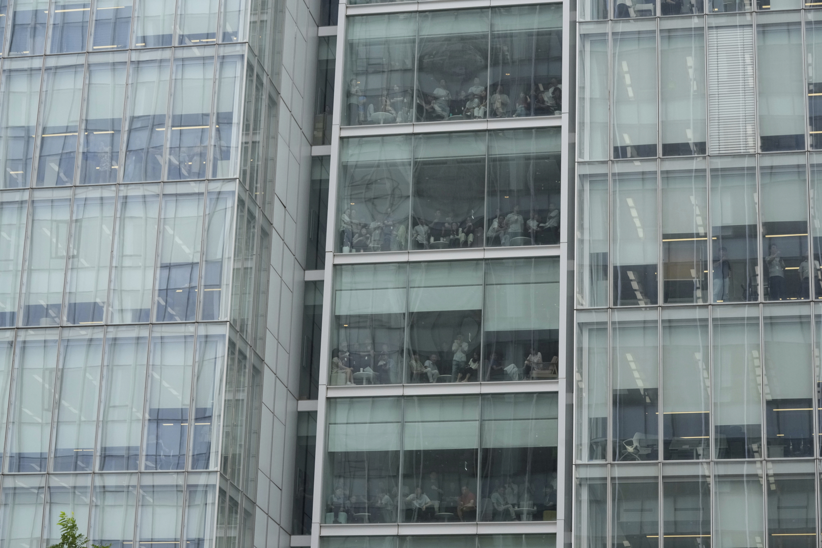 Office workers gather around windows to watch Kim Keon Hee, the wife of South Korea's ousted former President Yoon Suk Yeol, arriving at the special prosecutor's office in Seoul, South Korea, Wednesday, Aug. 6, 2025. (AP Photo/Ahn Young-joon)
