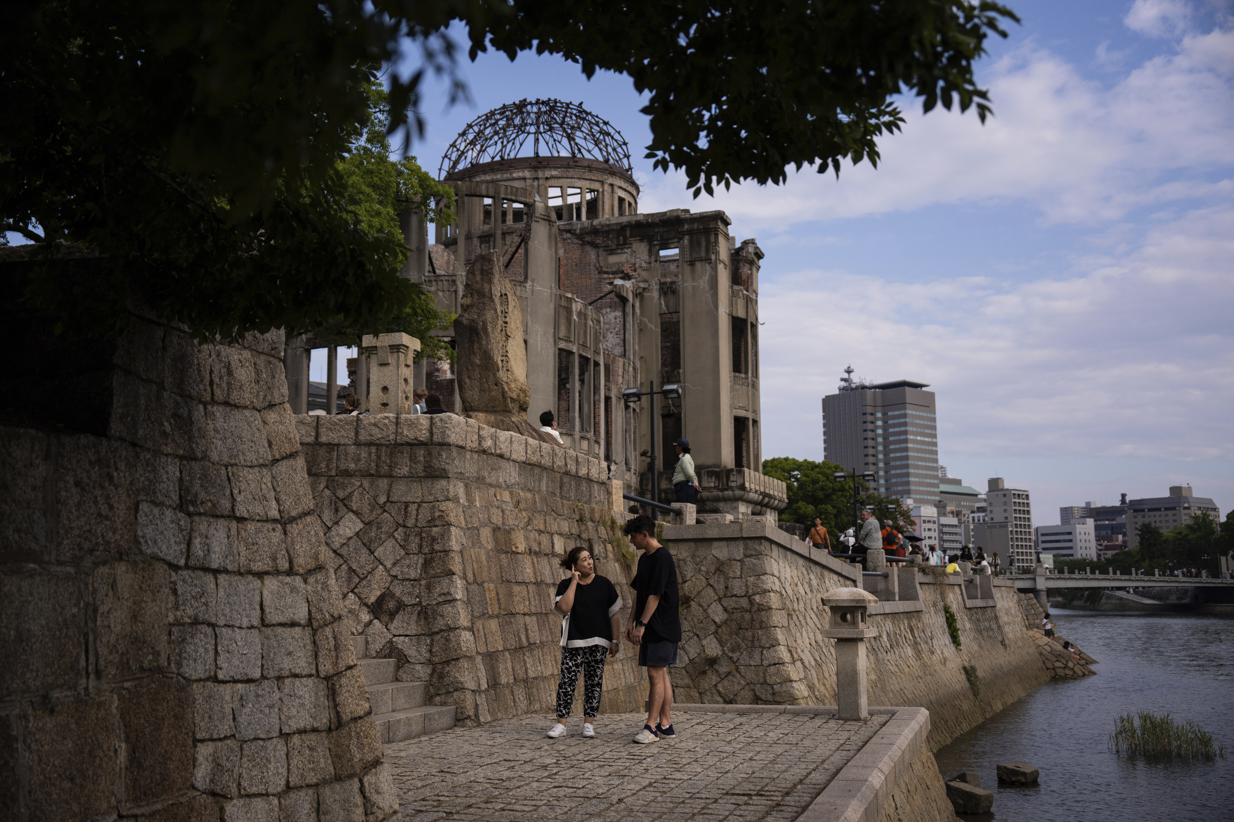 Ari Beser, left, and Kosuzu Harada, right, chat as they pose for photographs after an interview with The Associated Press in front of the Atomic Bomb Dome in Hiroshima, western Japan Tuesday, Aug. 5, 2025. (AP Photo/Louise Delmotte)