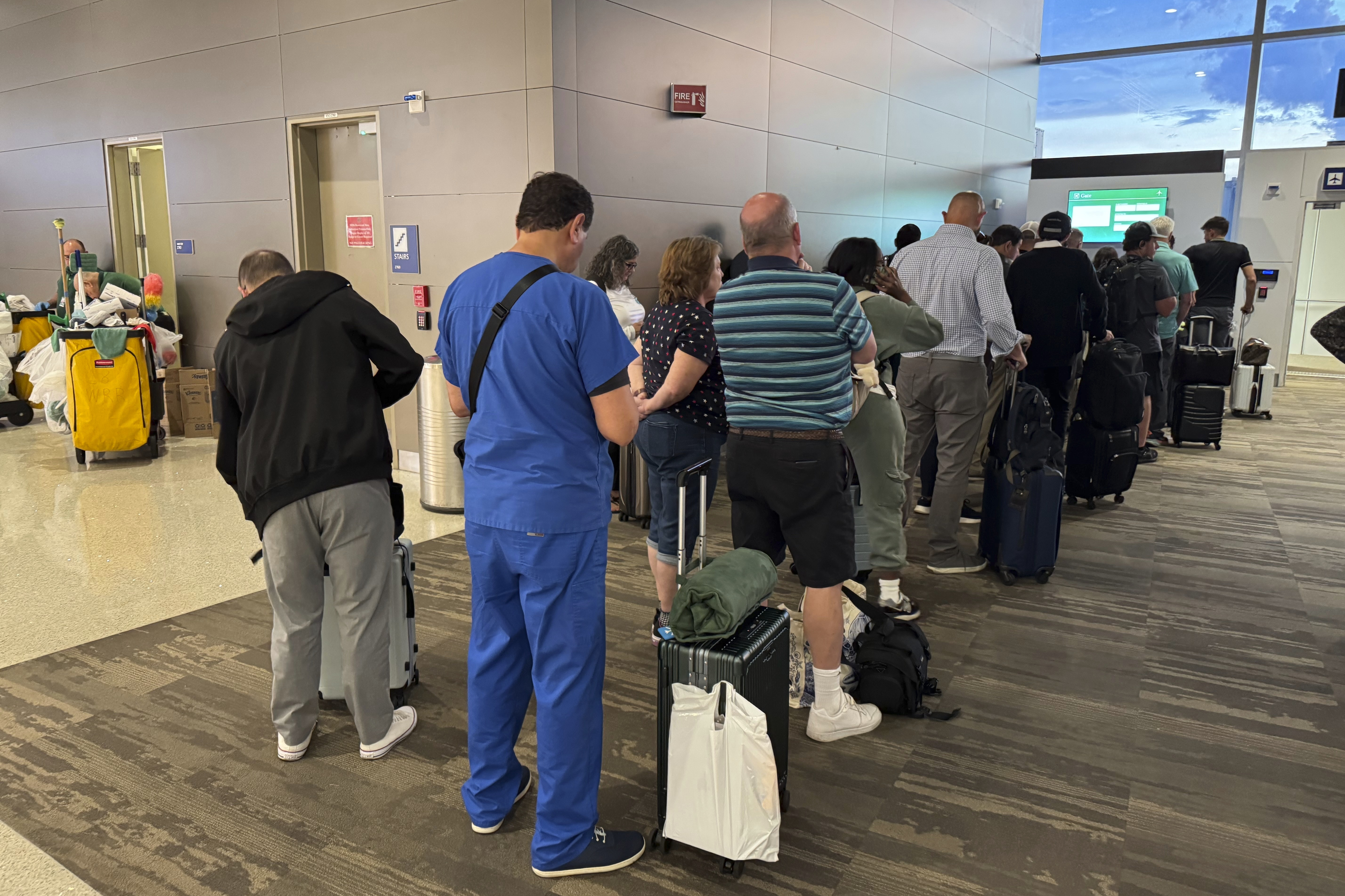 Passengers seeks updates on their delayed flight at Louis Armstrong New Orleans International Airport, Wednesday, Aug. 6, 2025, in Kenner, La. (AP Photo/Jack Brooks)