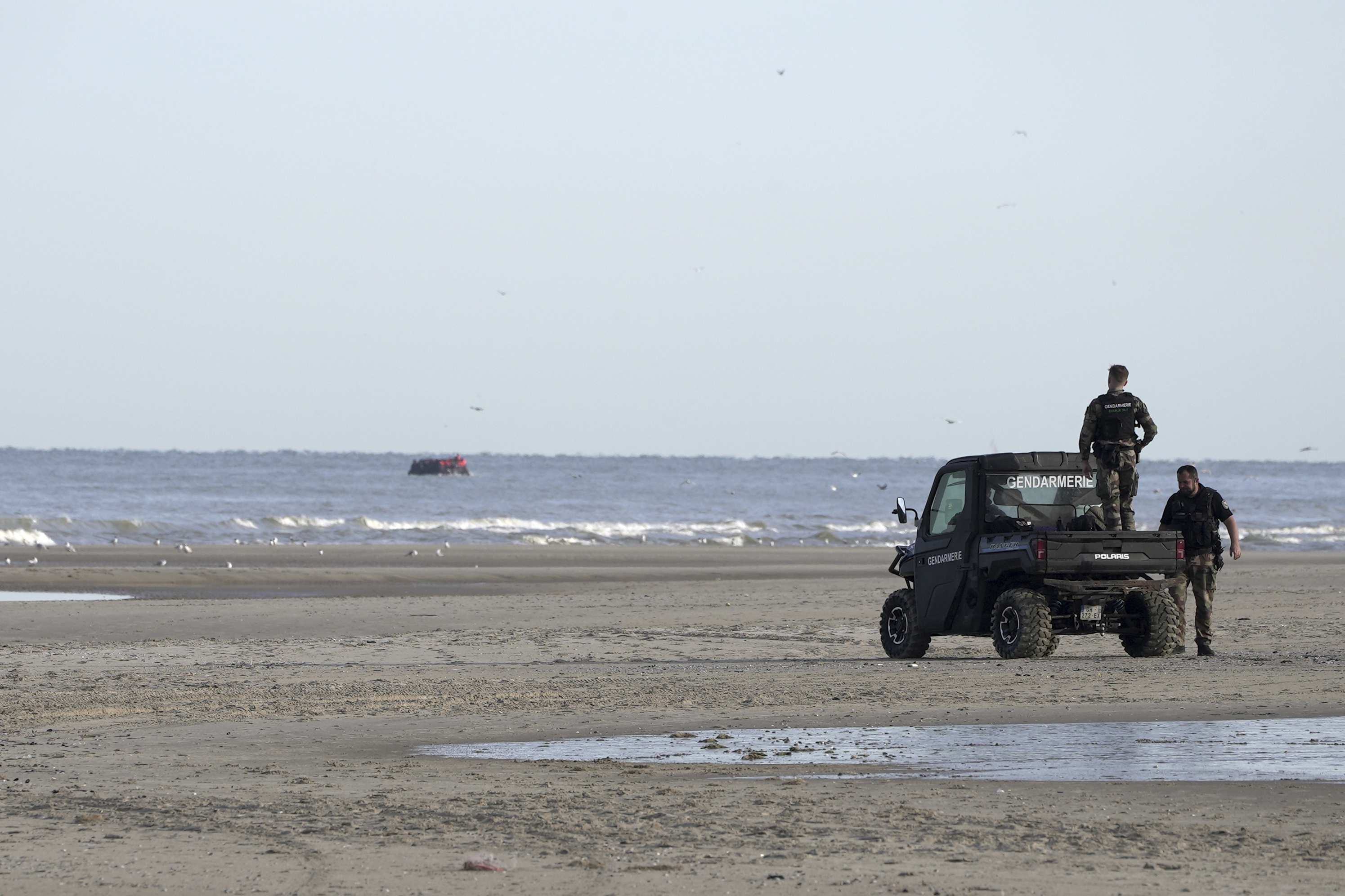 FILE - Gendarmes watch migrants on a small boat from Ecault beach, Friday July 4, 2025. (AP photo/John Leicester, File)