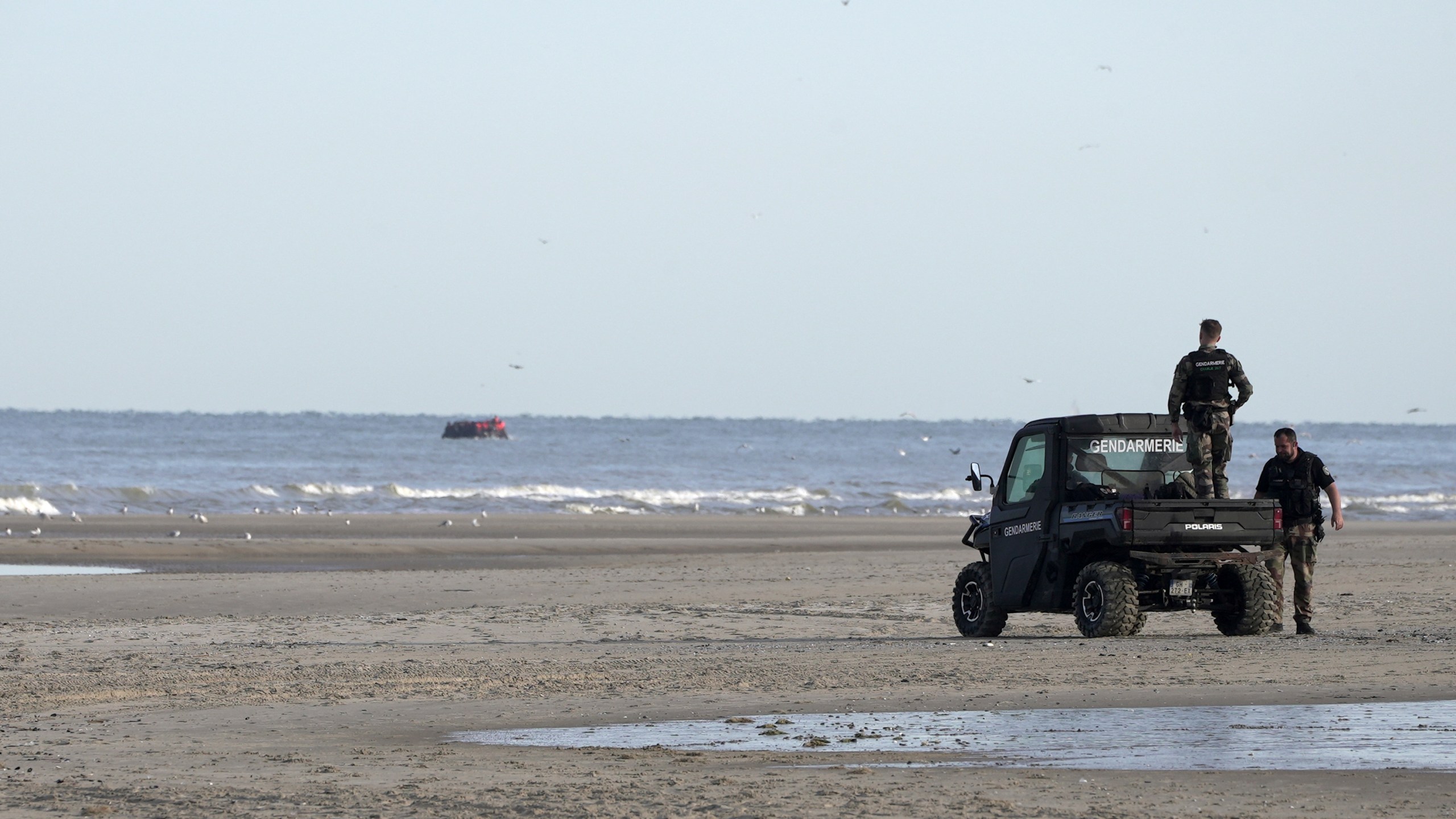 FILE - Gendarmes watch migrants on a small boat from Ecault beach, Friday July 4, 2025. (AP photo/John Leicester, File)