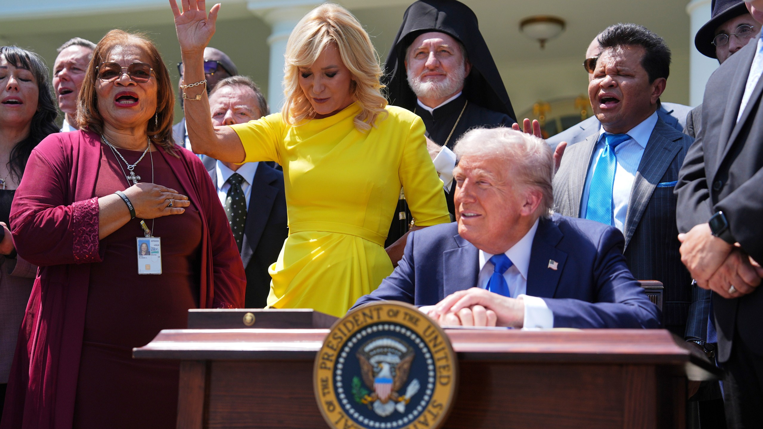 FILE - President Donald Trump sits at a desk as he and religious leaders listen to a musical performance before Trump signs an executive order during a National Day of Prayer event in the Rose Garden of the White House, May 1, 2025, in Washington. (AP Photo/Evan Vucci, File)