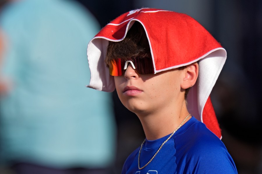 FILE - A young Tampa Bay Buccaneers fan covers his head to avoid the sun and heat during Back Together Weekend at an NFL football training camp practice Sunday, July 27, 2025, in Tampa, Fla. (AP Photo/Chris O'Meara, File)