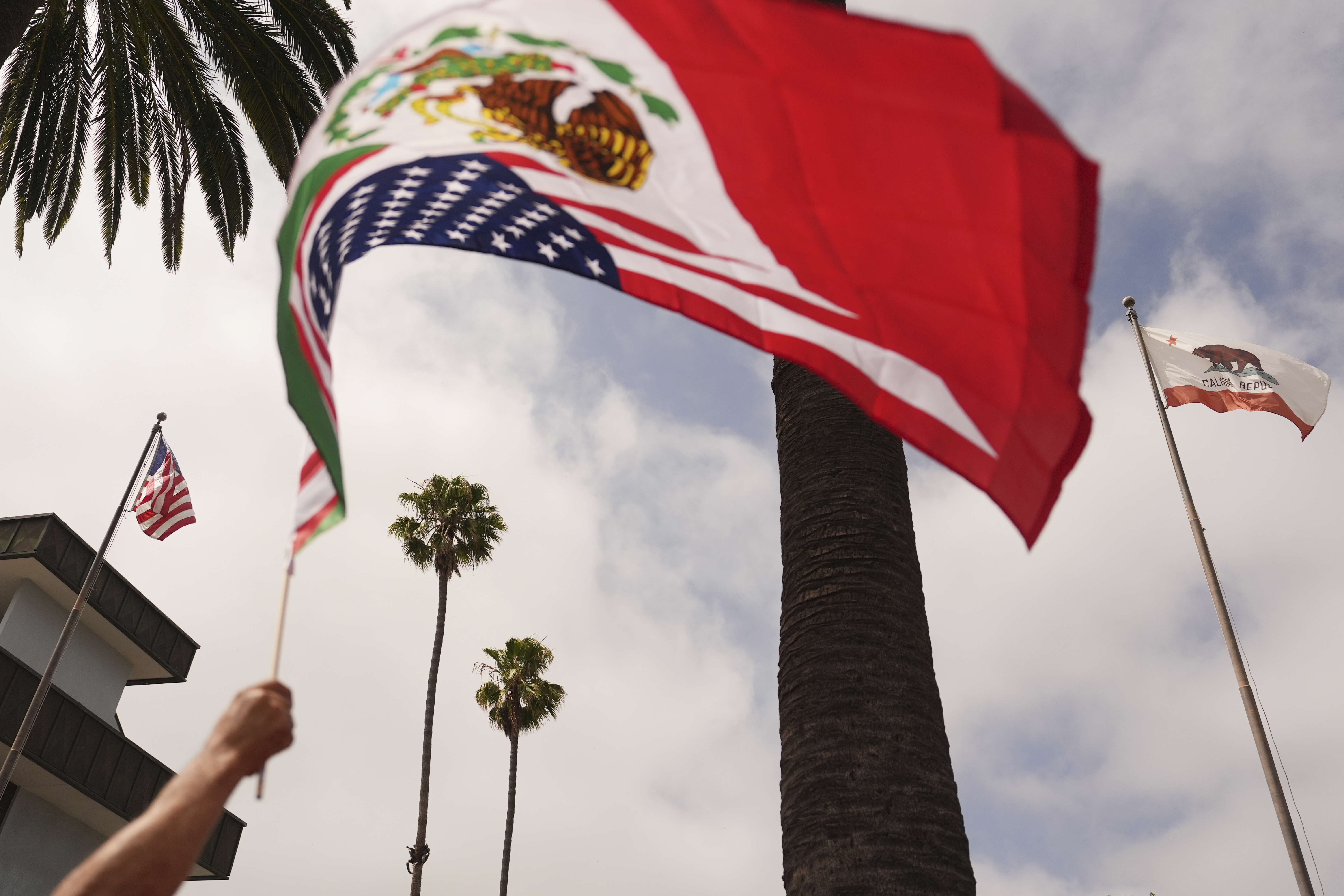A demonstrator waves a flag during a protest in reaction to recent immigration raids on Friday, July 11, 2025, in Oxnard, Calif. (AP Photo/Jae C. Hong)