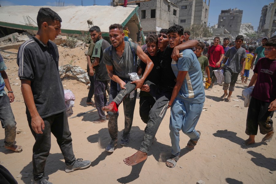 Palestinians carry a wounded man who was injured while rushing to collect humanitarian aid airdropped by parachute into Gaza City, in the northern Gaza Strip, Thursday, Aug. 7, 2025. (AP Photo/Jehad Alshrafi)