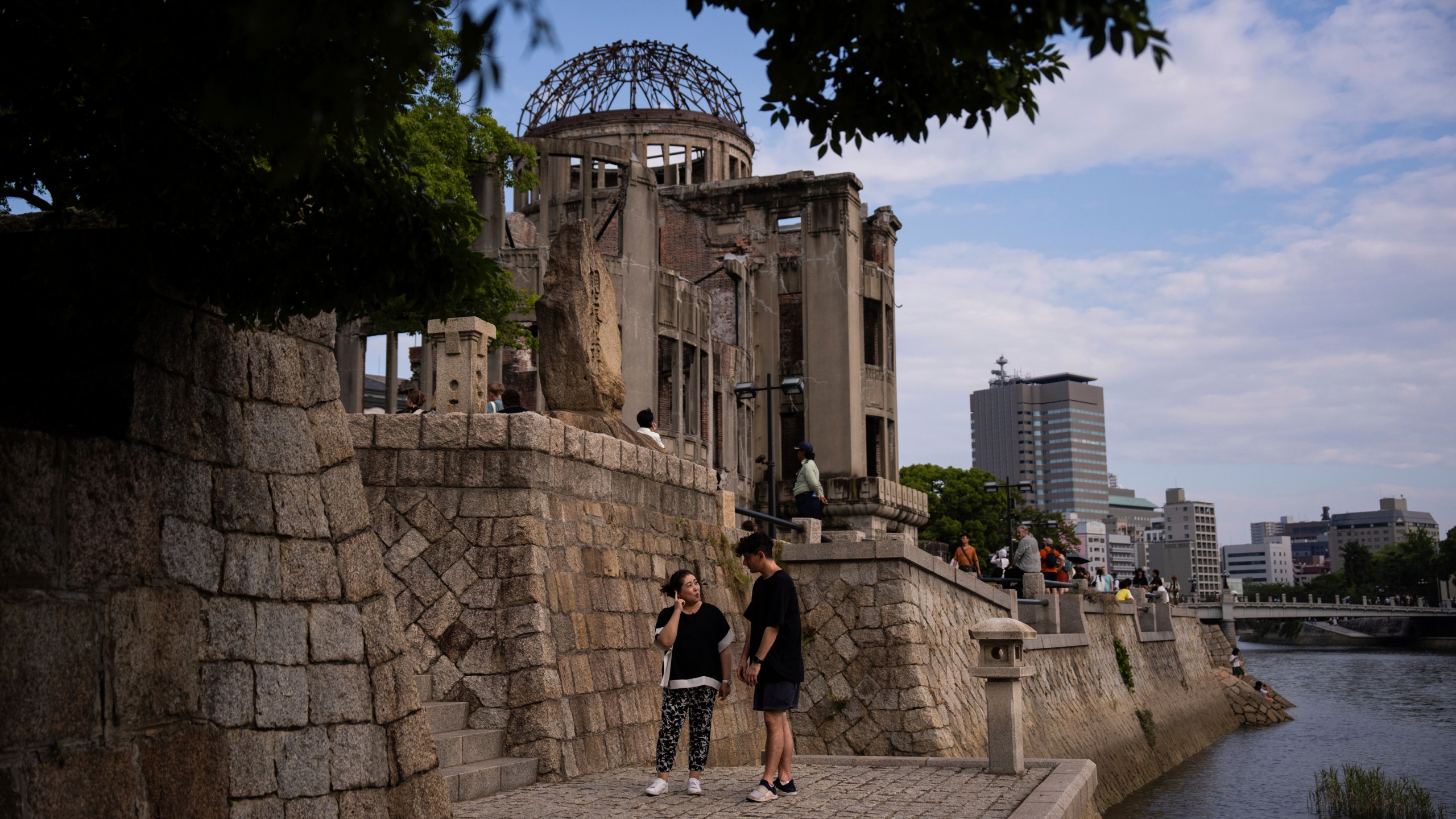 Ari Beser, left, and Kosuzu Harada, right, chat as they pose for photographs after an interview with The Associated Press in front of the Atomic Bomb Dome in Hiroshima, western Japan Tuesday, Aug. 5, 2025. (AP Photo/Louise Delmotte)