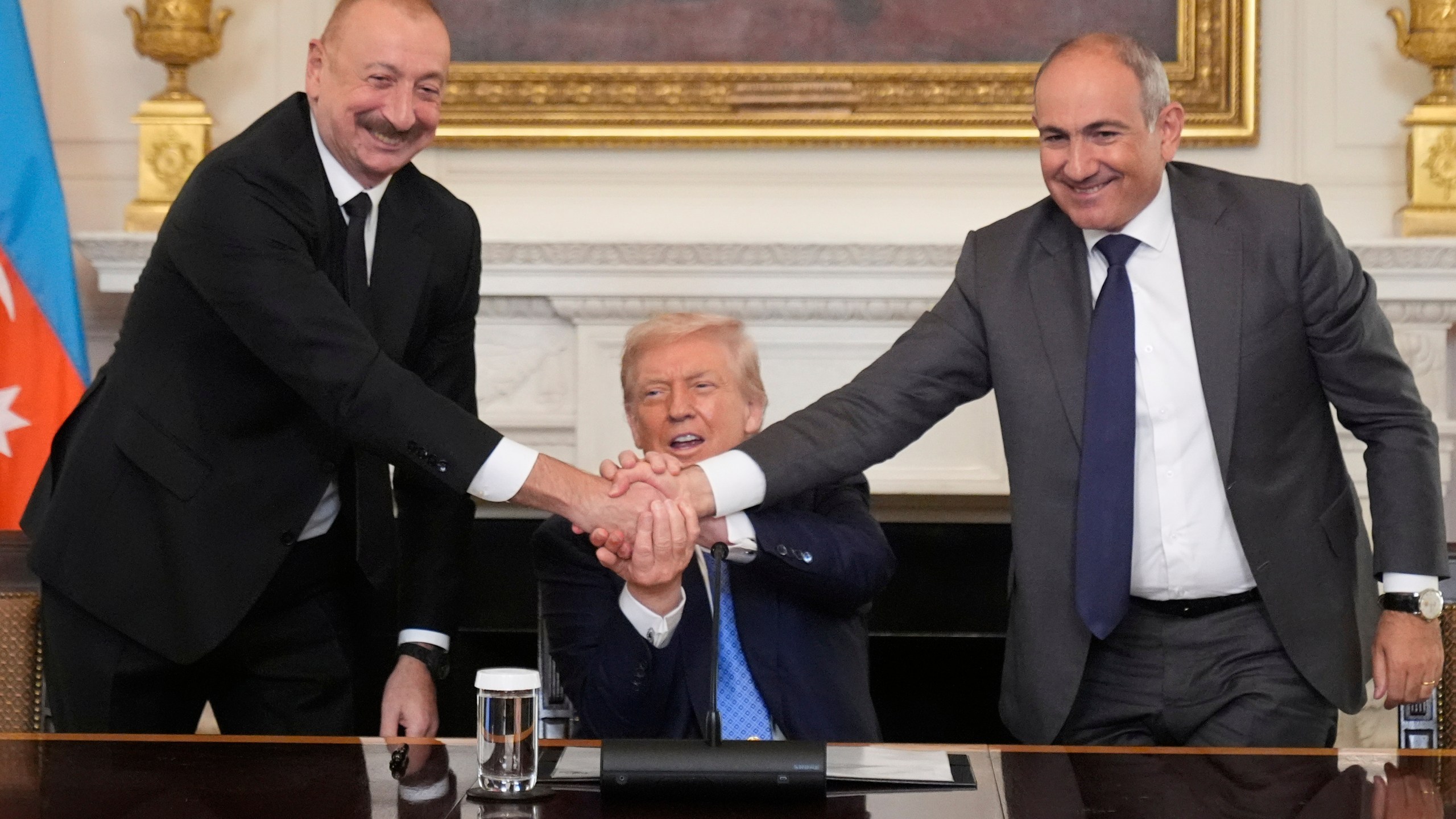 President Donald Trump, center, shakes hands with Armenian Prime Minister Nikol Pashinyan, right, and Azerbaijan President Ilham Aliyev during a trilateral signing ceremony in the State Dining Room of the White House, Friday, Aug. 8, 2025, in Washington. (AP Photo/Mark Schiefelbein)