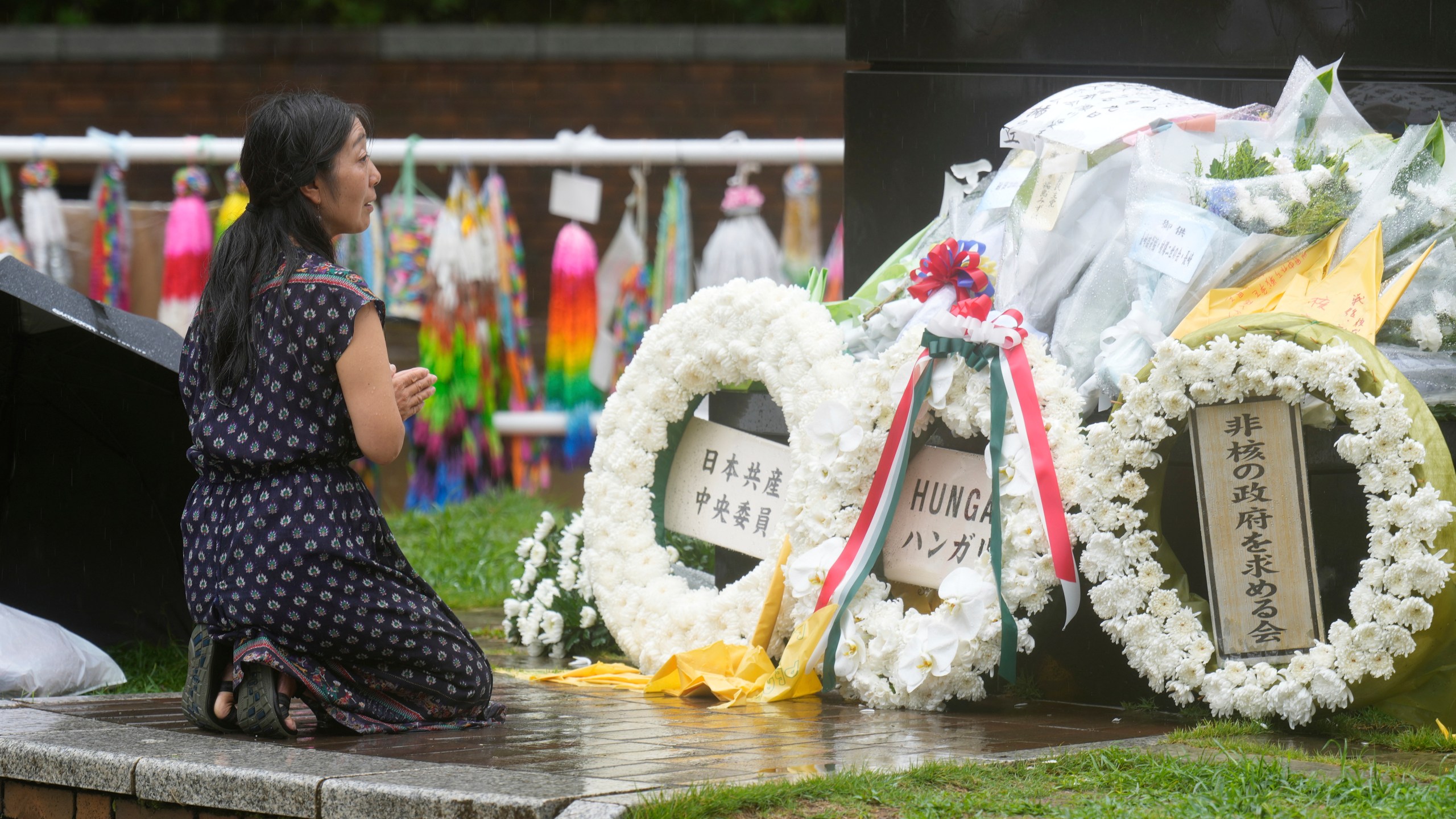 A woman offers prayer in the rain at the Atomic Bomb Hypocenter Park, as Japan commemorates the 80th anniversary of the day an atomic bomb was dropped on its southwestern city, in Nagasaki, Japan Saturday, Aug. 9, 2025.(AP Photo/Eugene Hoshiko)