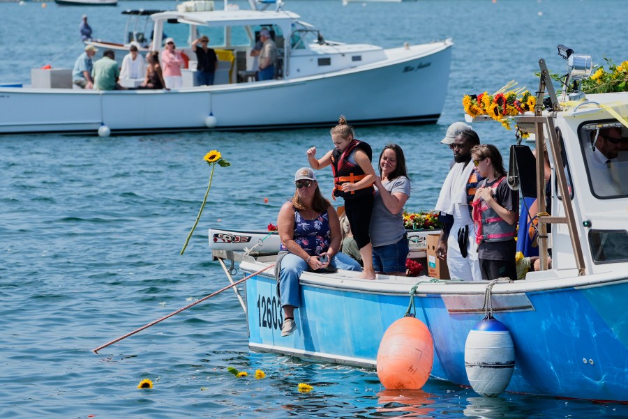 A girl tosses a sunflower into the water in honor of Sunshine Stewart, Sunday, Aug. 10, 2025, in St. George, Maine. (AP Photo/Robert F. Bukaty)