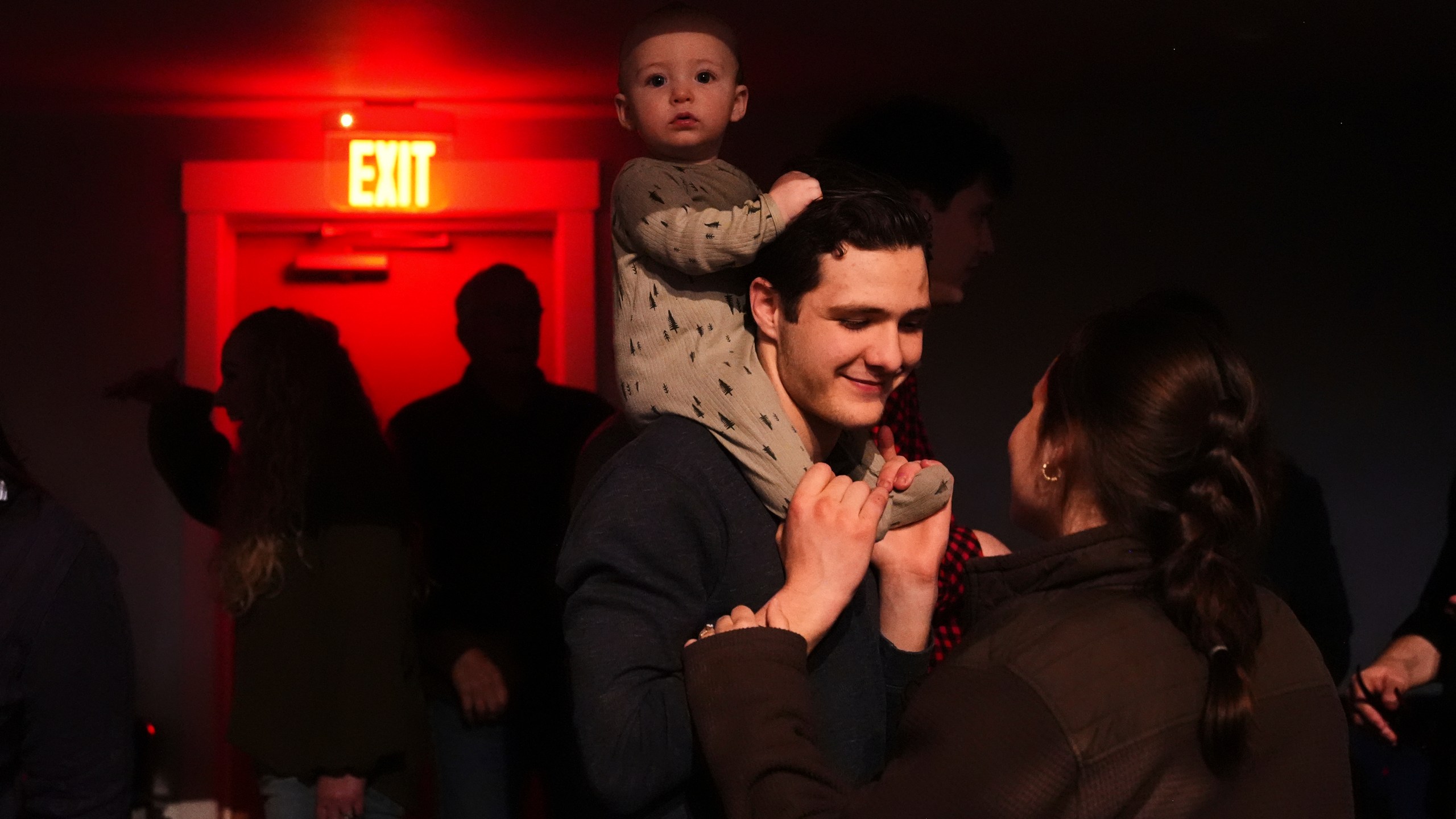 Elijah Mooring, whose family attends King's Cross, an offshoot church from Christ Church, holds son Gideon, 9 months, while talking to wife Evangeline as they wait for a performance from Pastor Doug Wilson and the Dads Band, Friday, April 4, 2025, at the Nuart Theatre in Moscow, Idaho. (AP Photo/Lindsey Wasson)